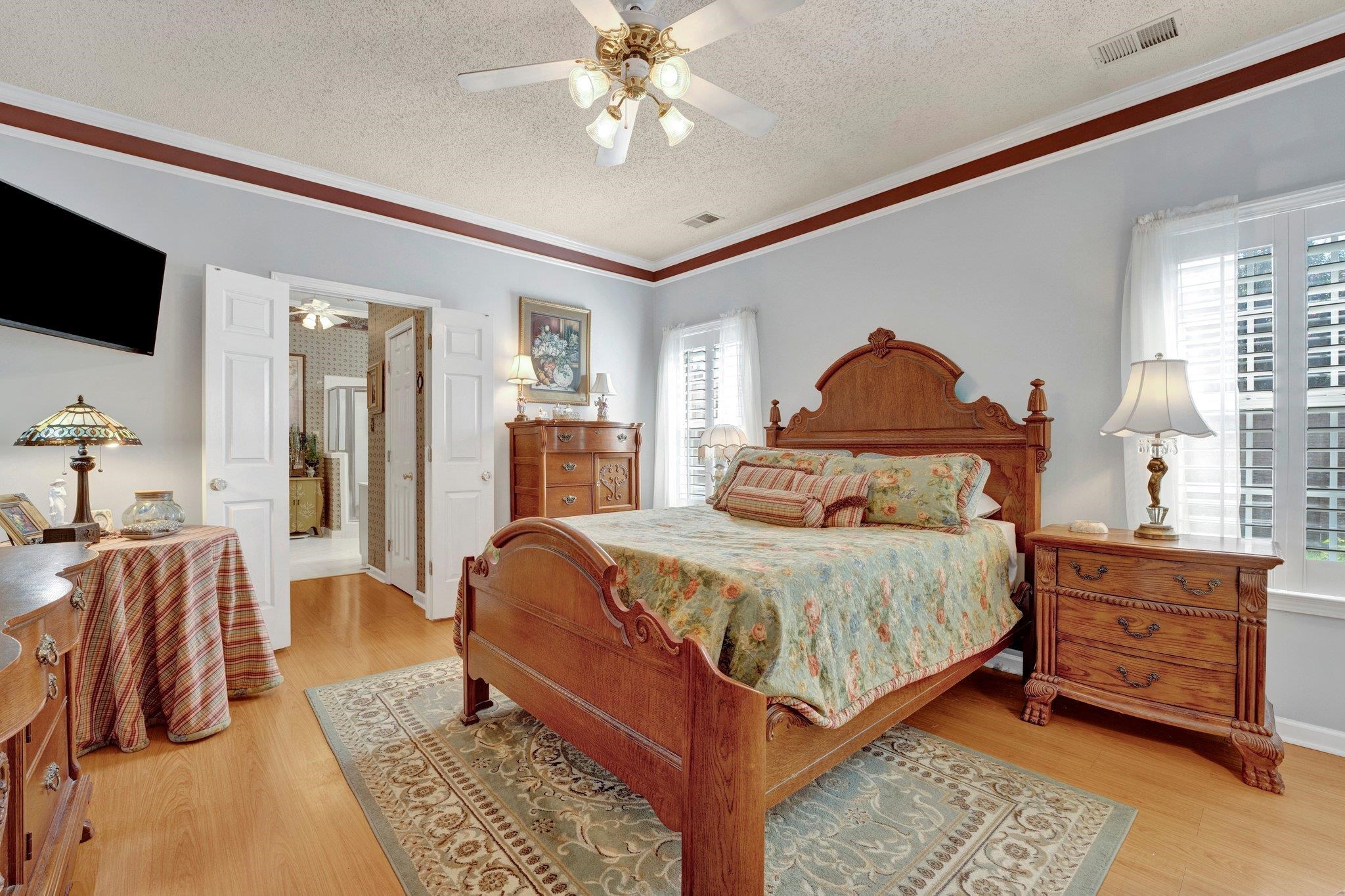 Bedroom featuring ceiling fan, light hardwood / wood-style floors, a textured ceiling, and crown molding