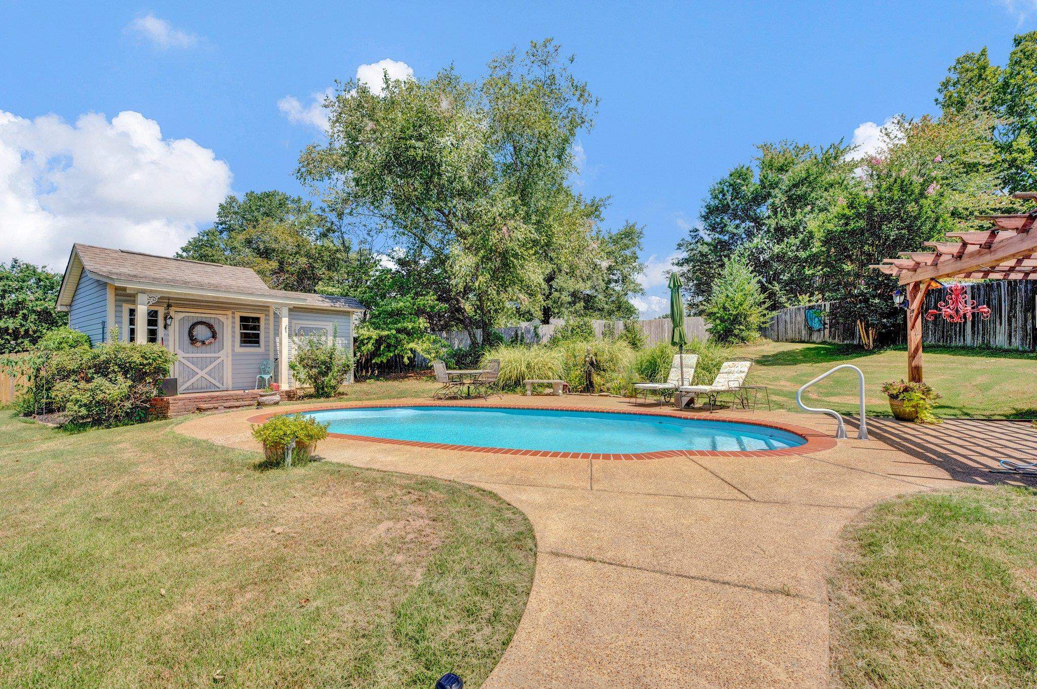 View of pool with a pergola and a yard