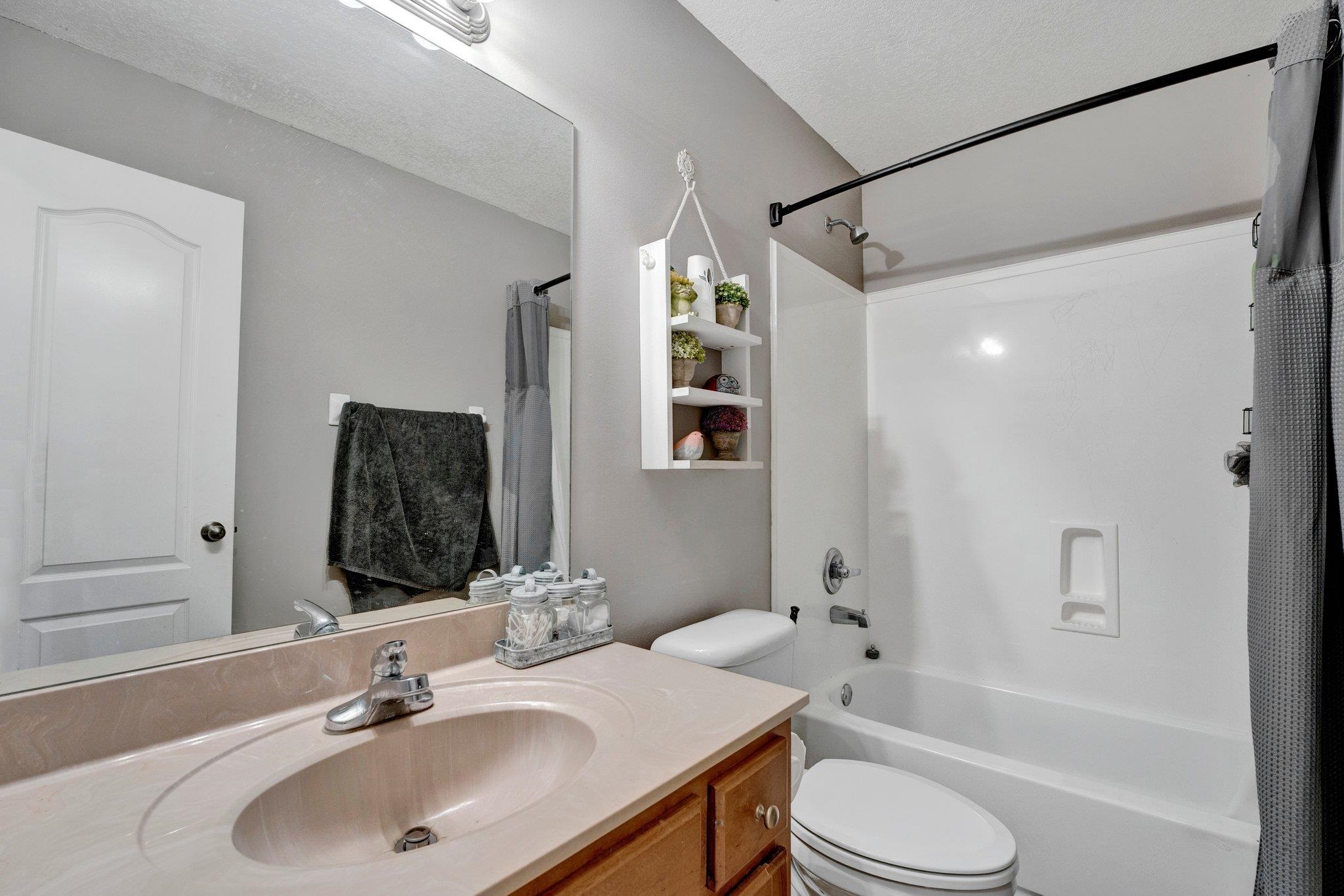 Full bathroom with toilet, shower / bathtub combination with curtain, vanity, and a textured ceiling