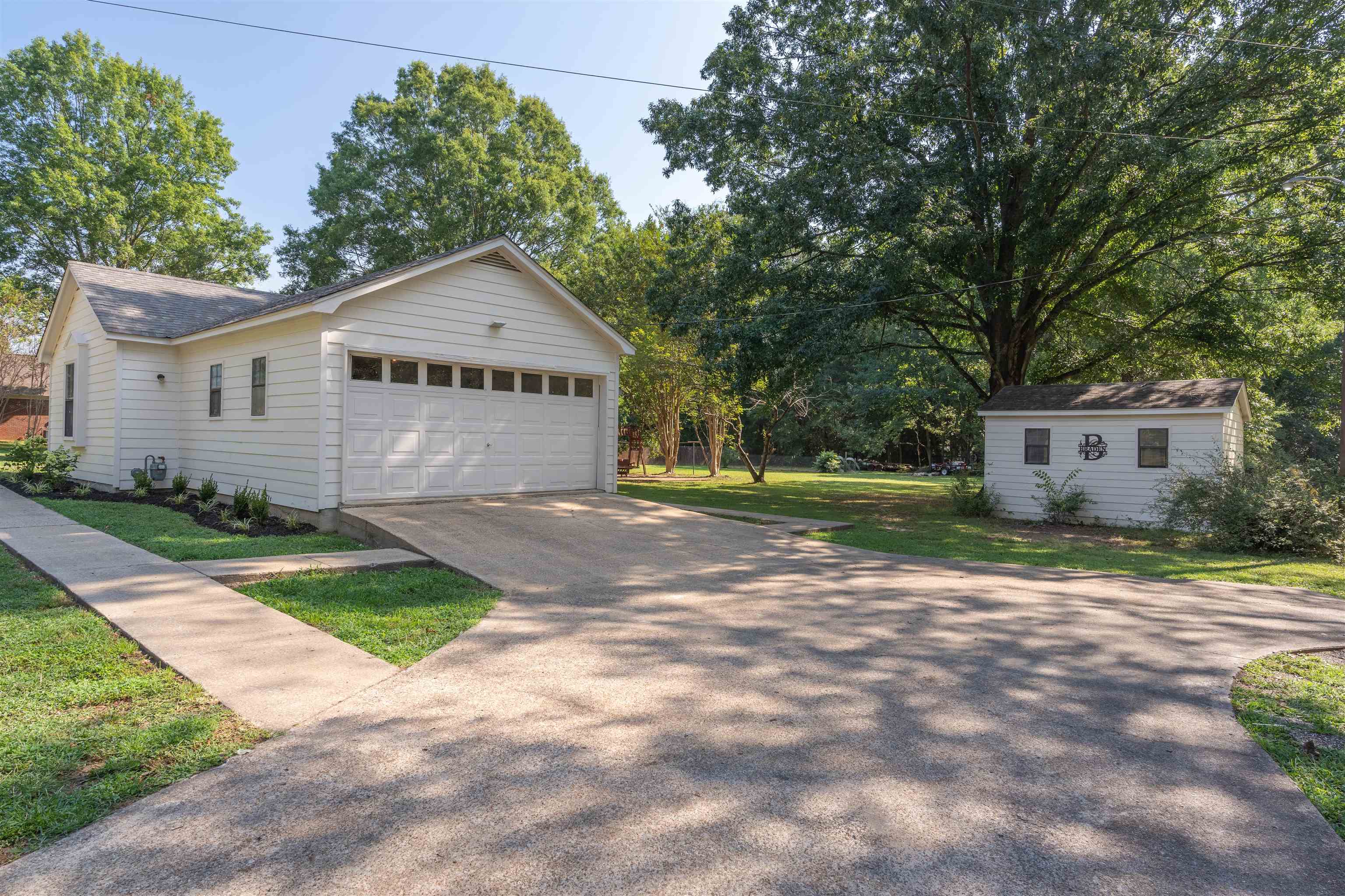 Exterior space featuring a garage, a front lawn, and an outbuilding