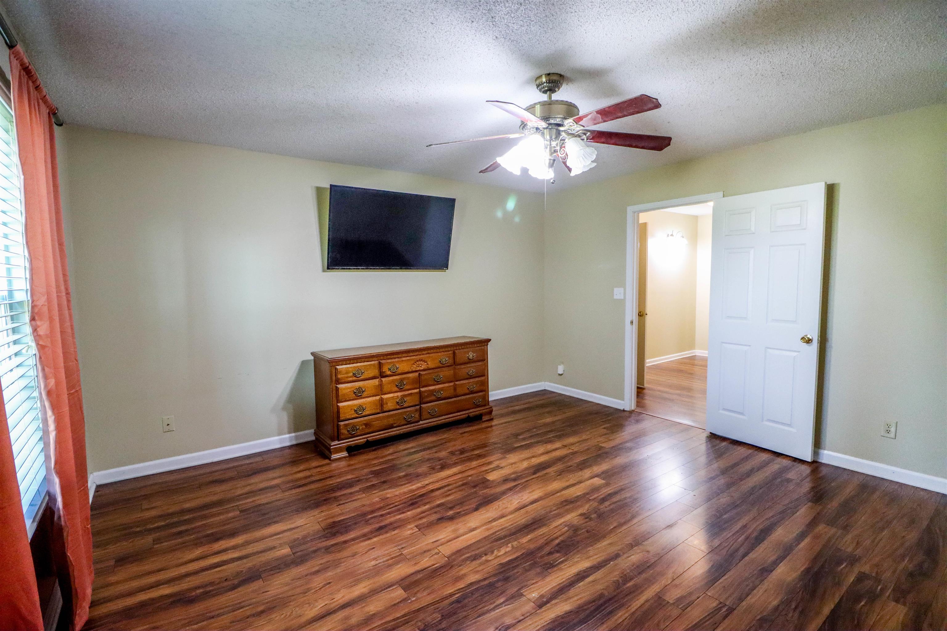 Unfurnished bedroom featuring a textured ceiling, ceiling fan, and dark hardwood / wood-style floors