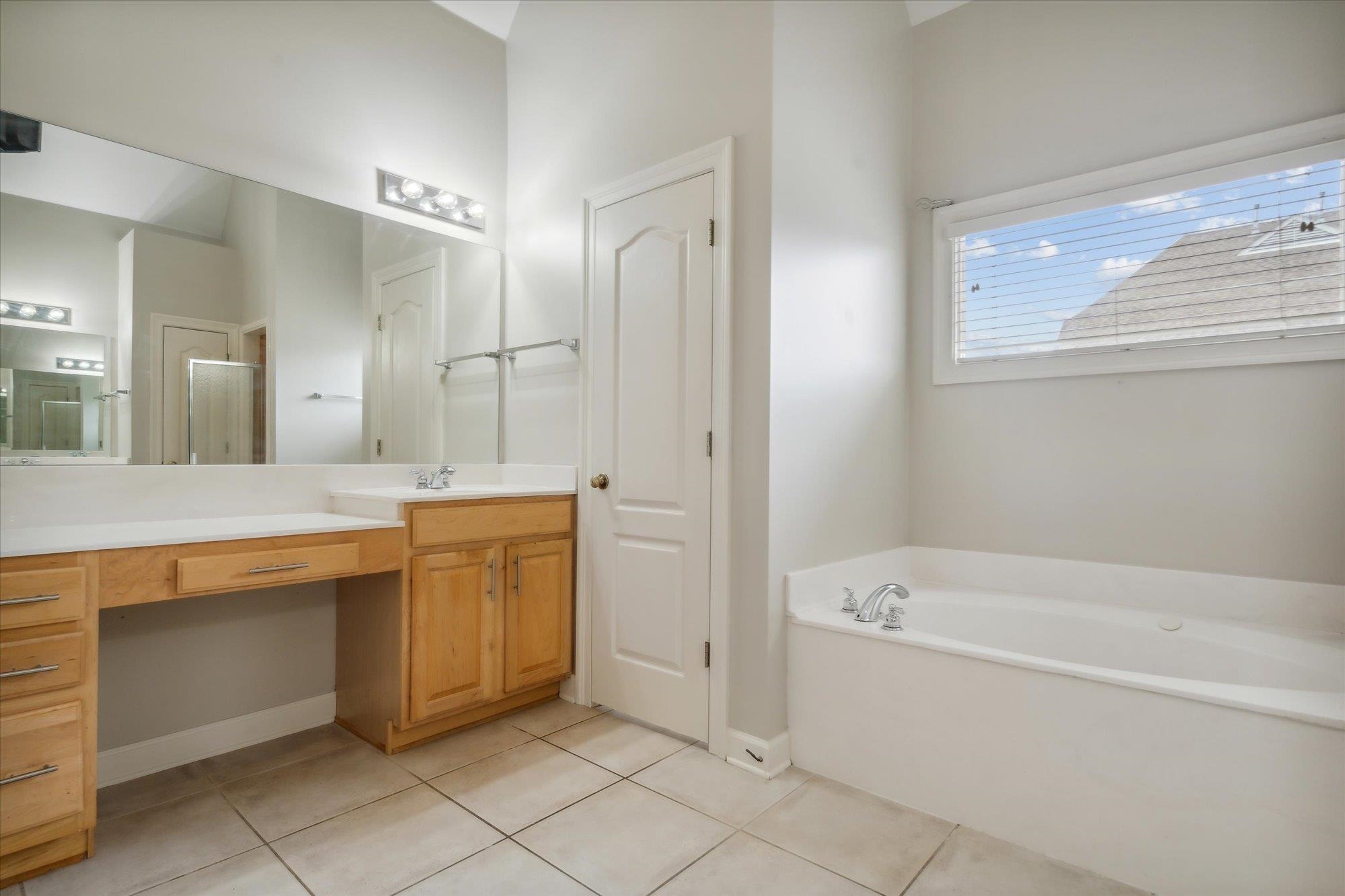 Bathroom with a tub, tile flooring, and vanity