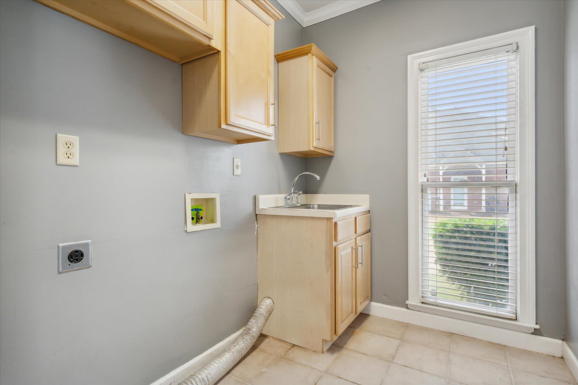 Washroom featuring cabinets, hookup for an electric dryer, hookup for a washing machine, sink, and light tile flooring