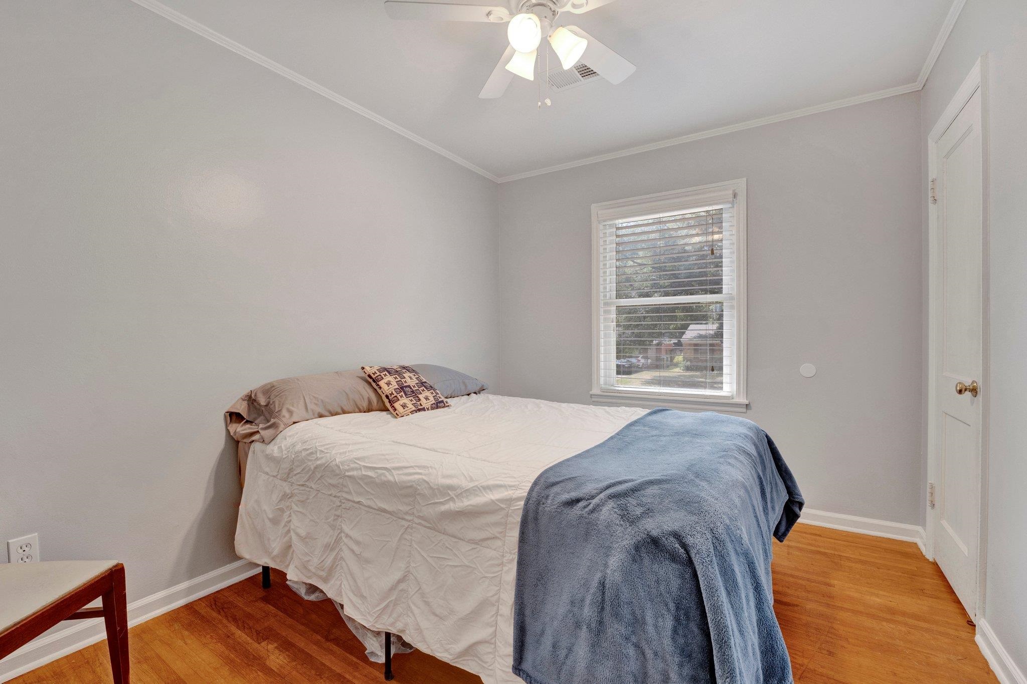 Bedroom featuring ceiling fan, light hardwood / wood-style flooring, and crown molding