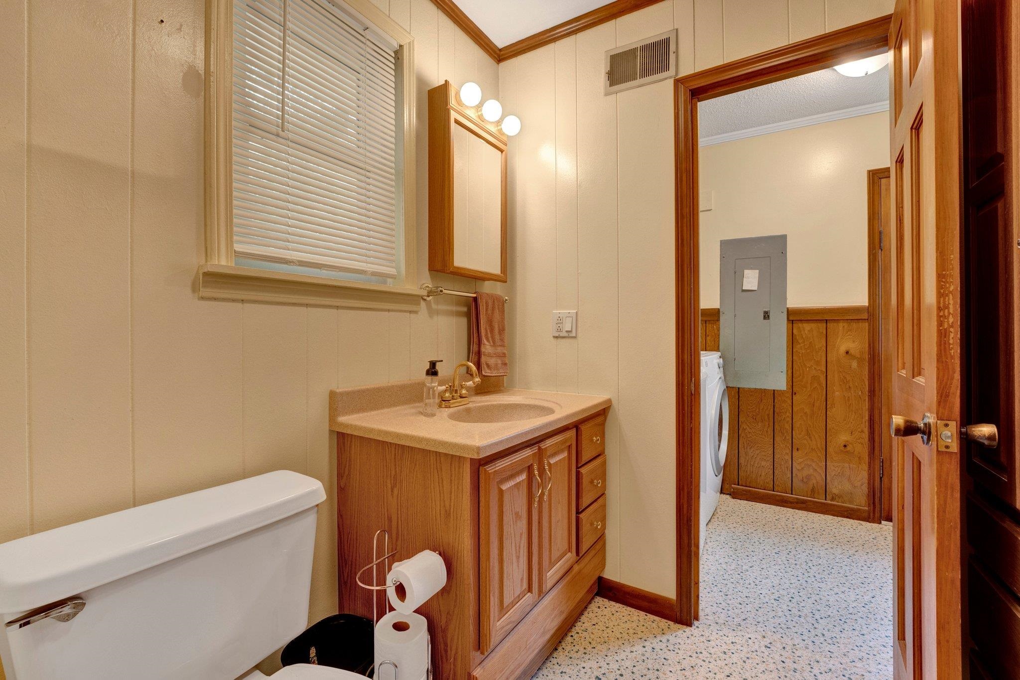 Bathroom featuring crown molding, toilet, vanity, and electric panel