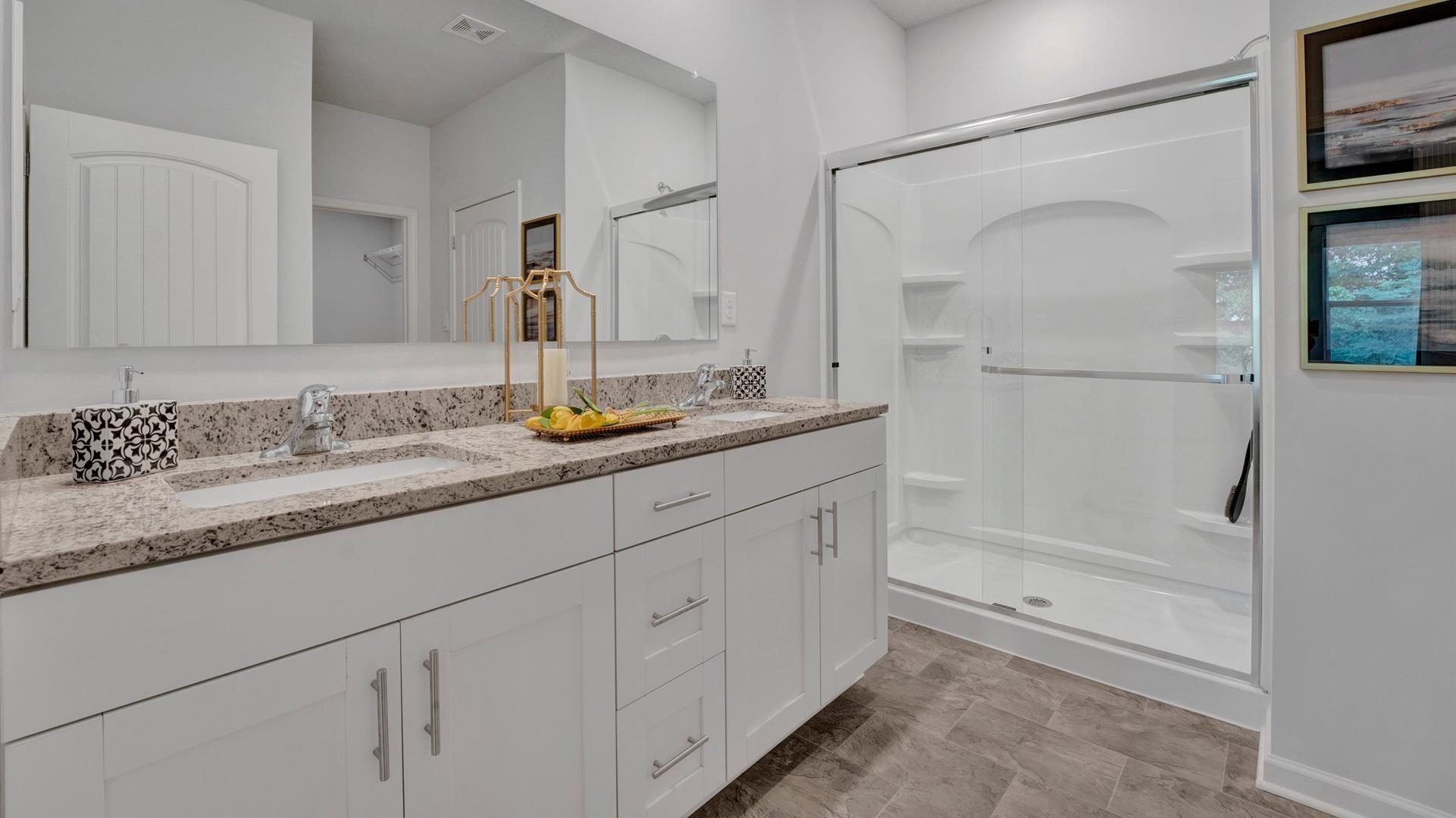 Bathroom featuring a shower with shower door, tile flooring, oversized vanity, and dual sinks