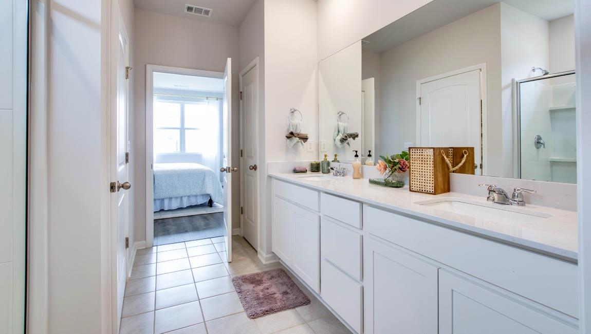 Bathroom with tile patterned floors, double sink vanity, and a shower with door