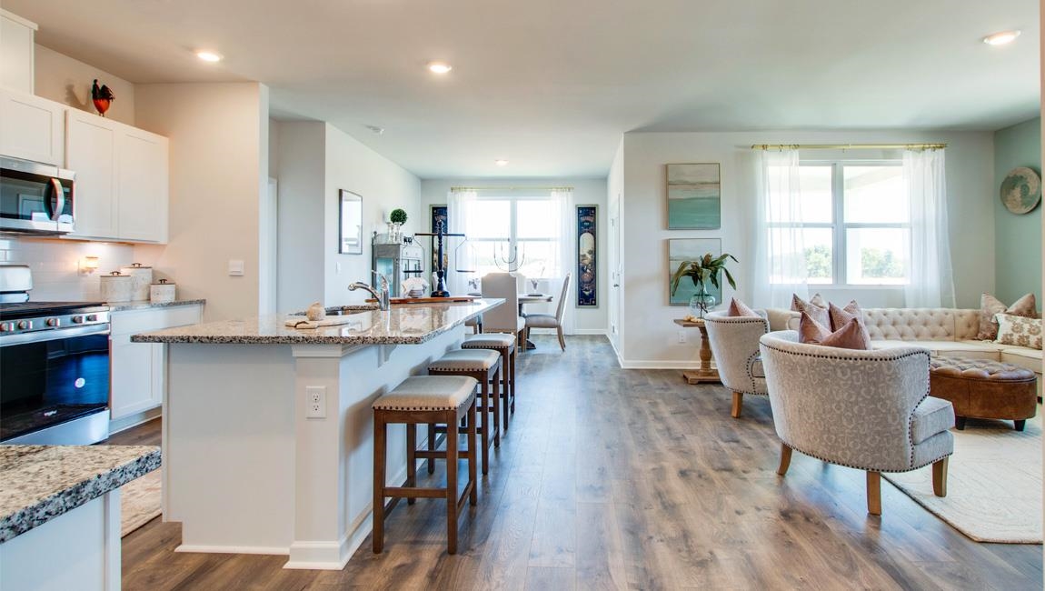 Kitchen featuring appliances with stainless steel finishes, light stone counters, hardwood / wood-style floors, and a healthy amount of sunlight
