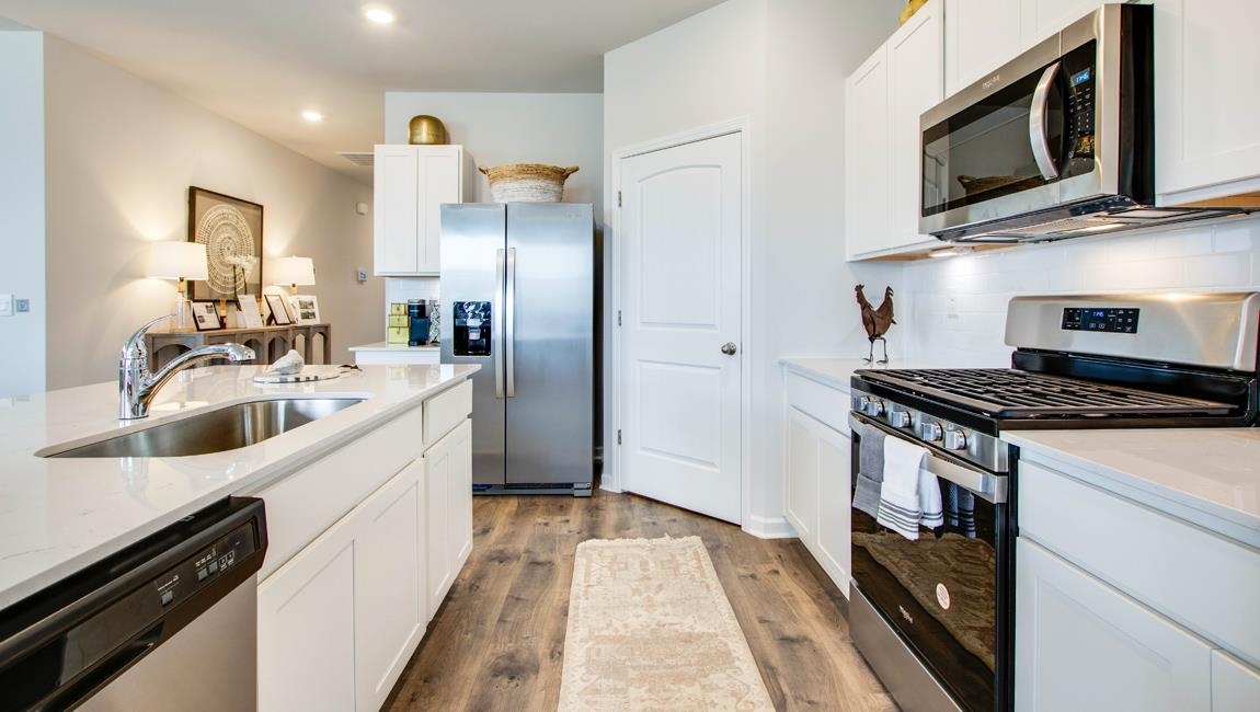 Kitchen with appliances with stainless steel finishes, sink, light hardwood / wood-style floors, and white cabinetry