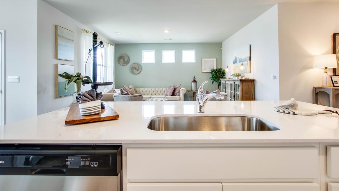 Kitchen with light stone counters, sink, stainless steel dishwasher, and white cabinetry