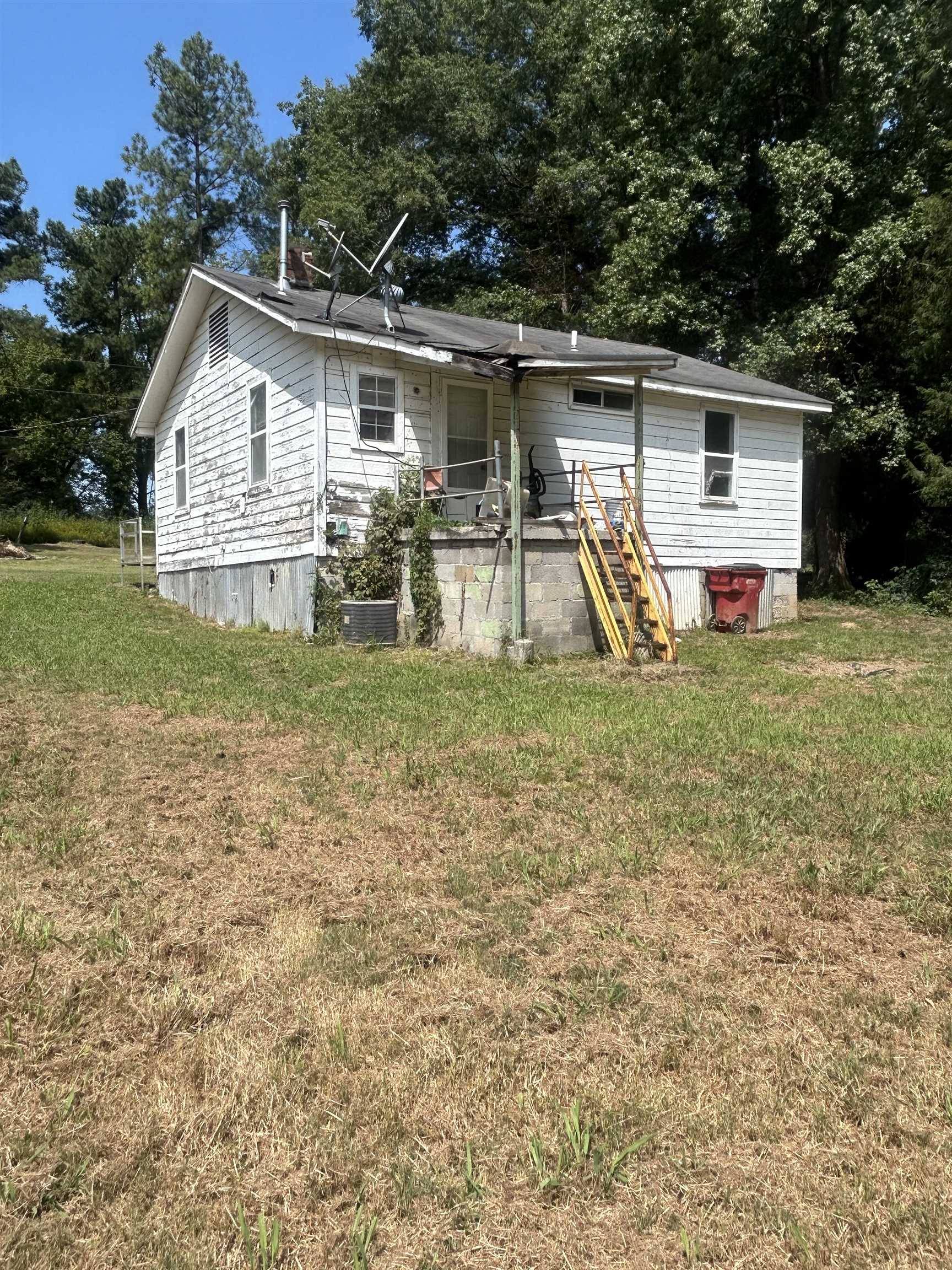 Rear view of property with a lawn and central AC