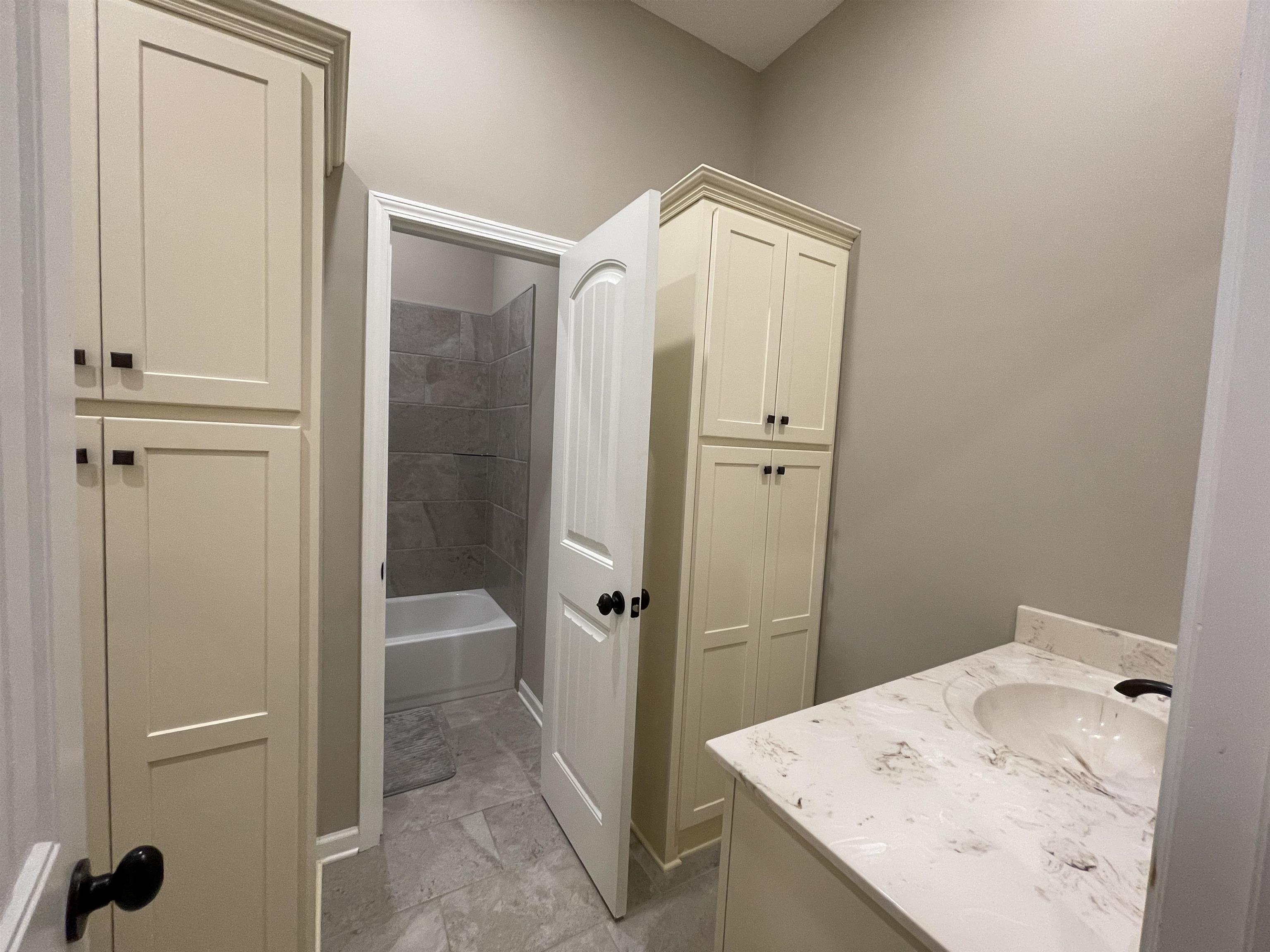 Bathroom featuring tile patterned floors,  shower combination, and vanity