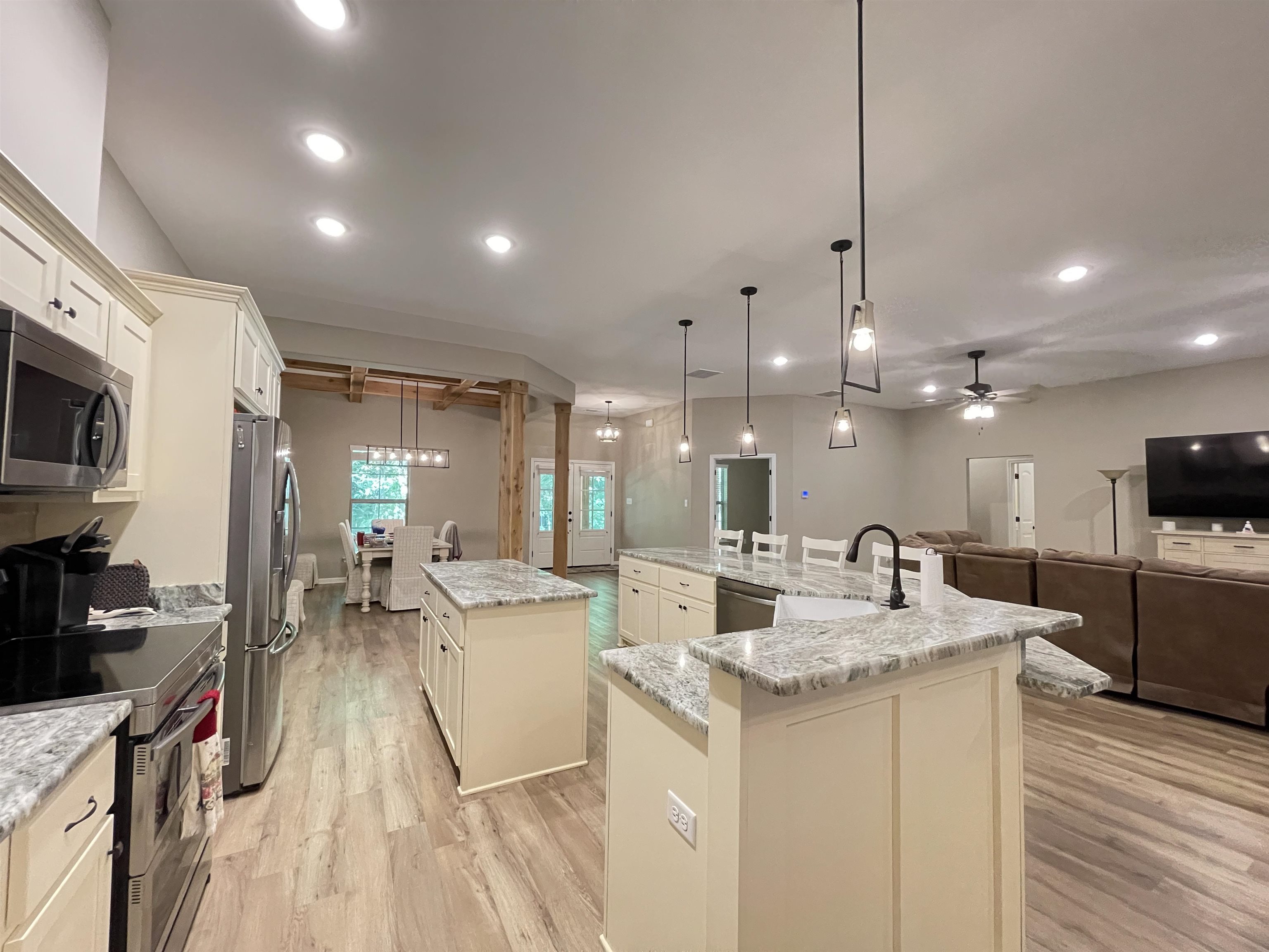 Kitchen with stainless steel appliances, a kitchen island with sink, livp flooring, and light granite countertops