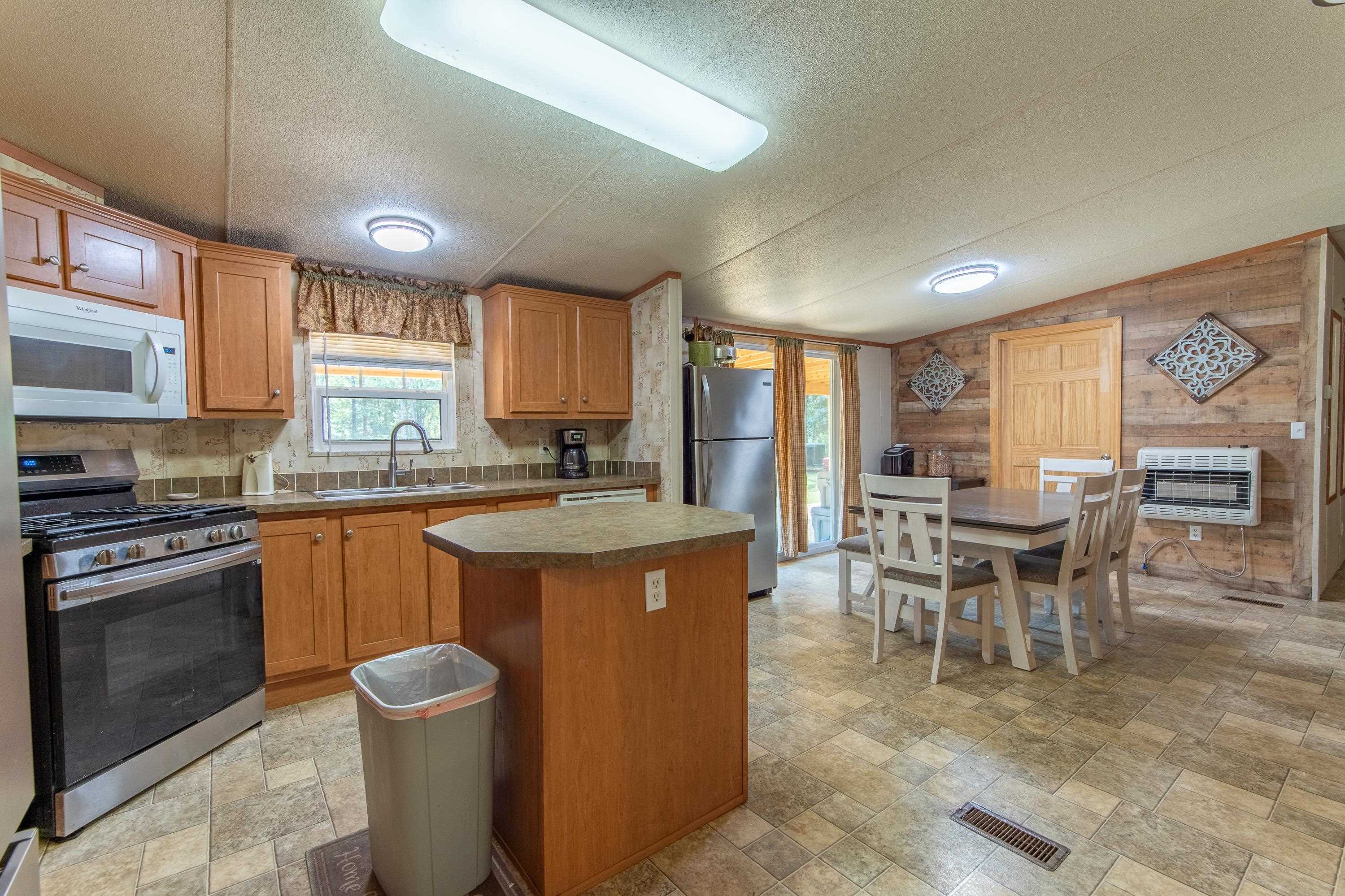 Kitchen with stainless steel appliances, decorative backsplash, sink, wooden walls, and a center island