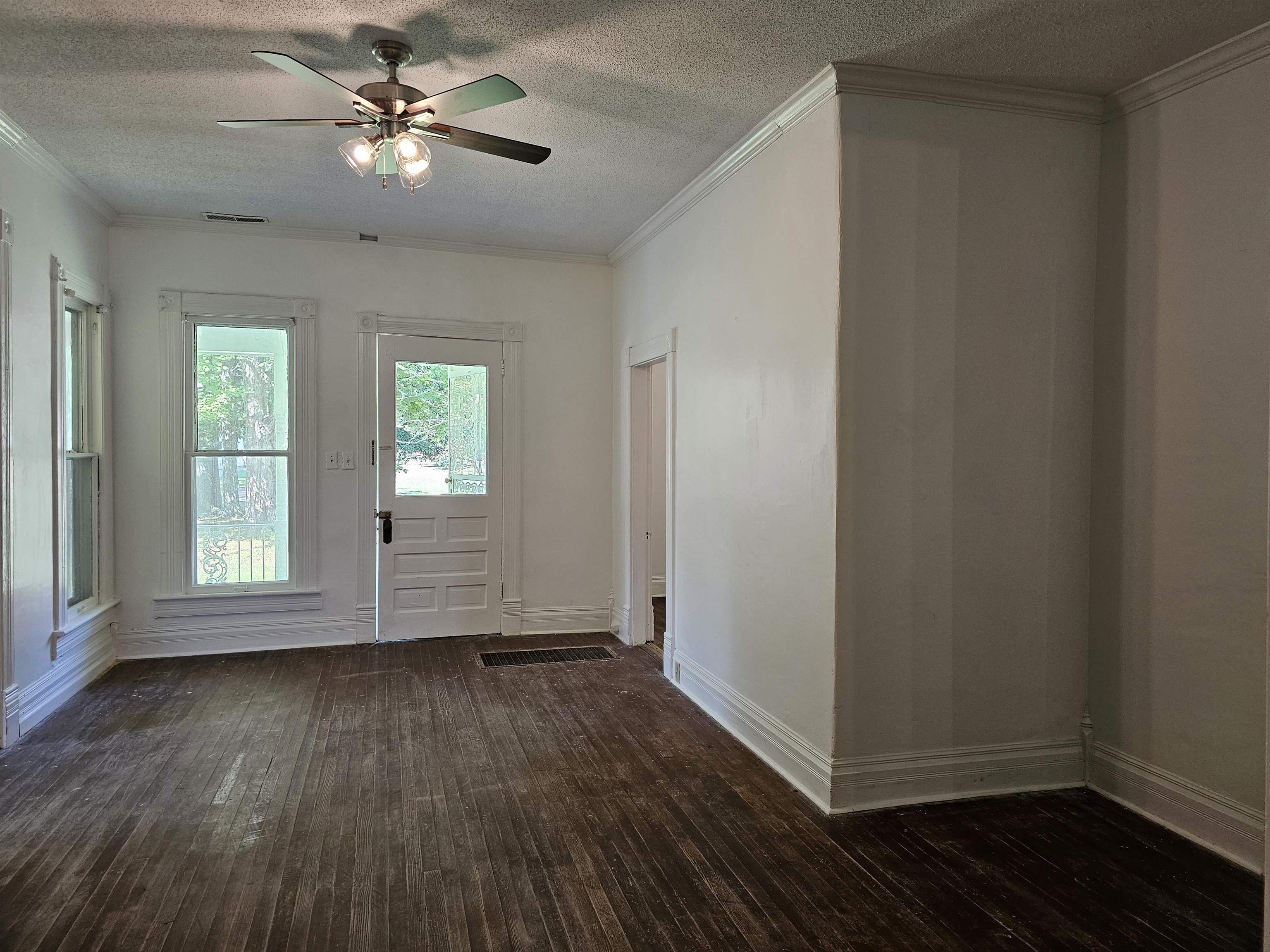 Doorway featuring ceiling fan, a textured ceiling, crown molding, and dark wood-type flooring