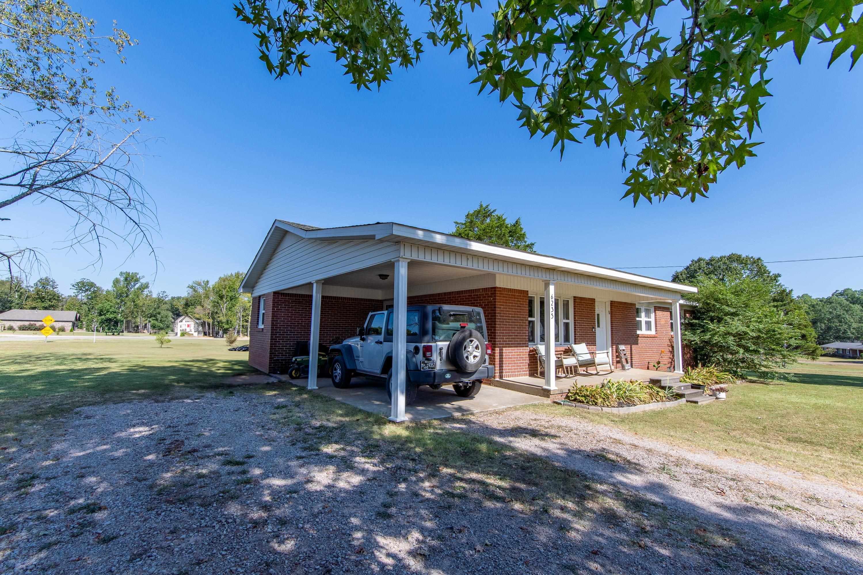 View of front of property featuring covered porch, a carport, and a front lawn