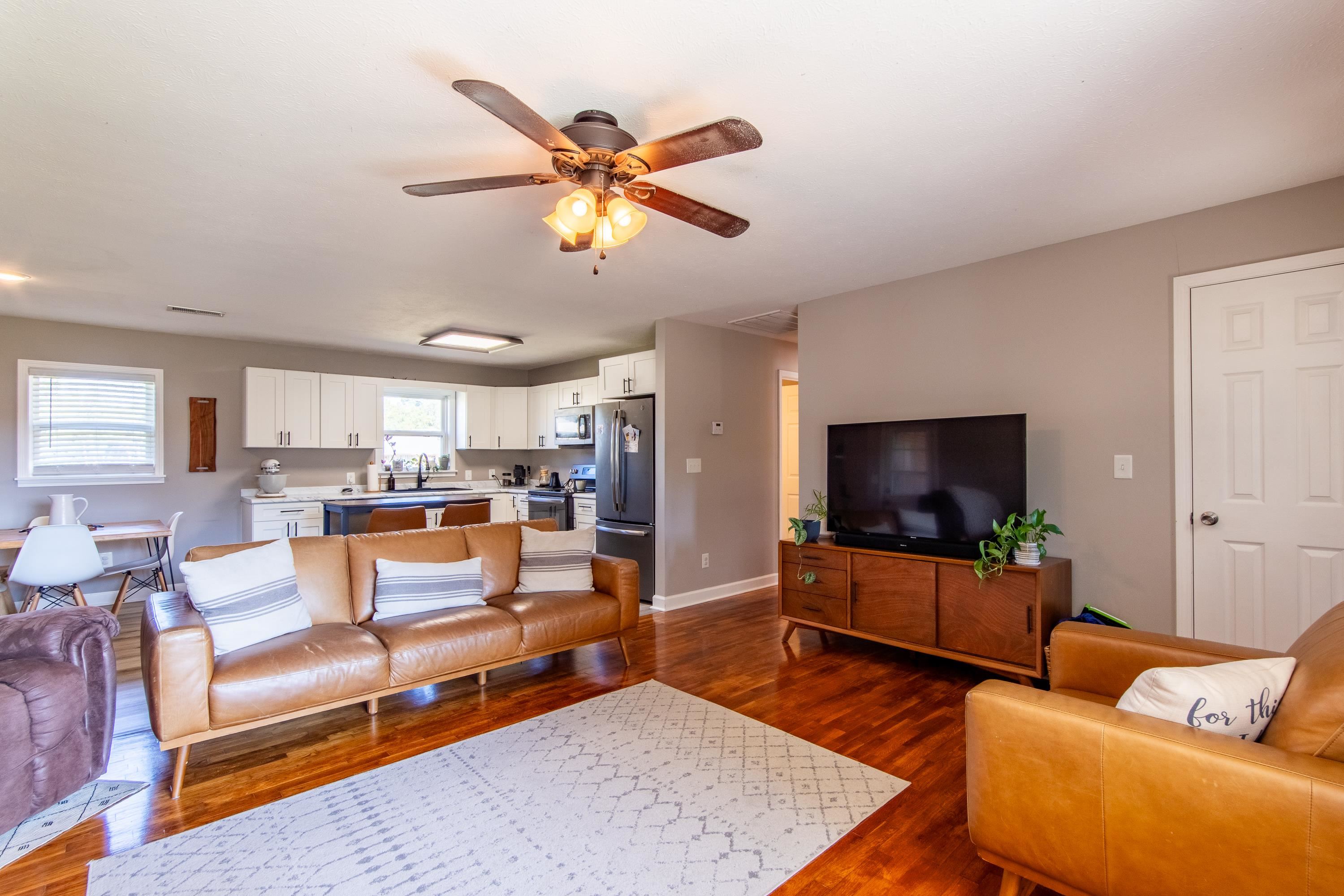 Living room featuring ceiling fan and dark wood-type flooring