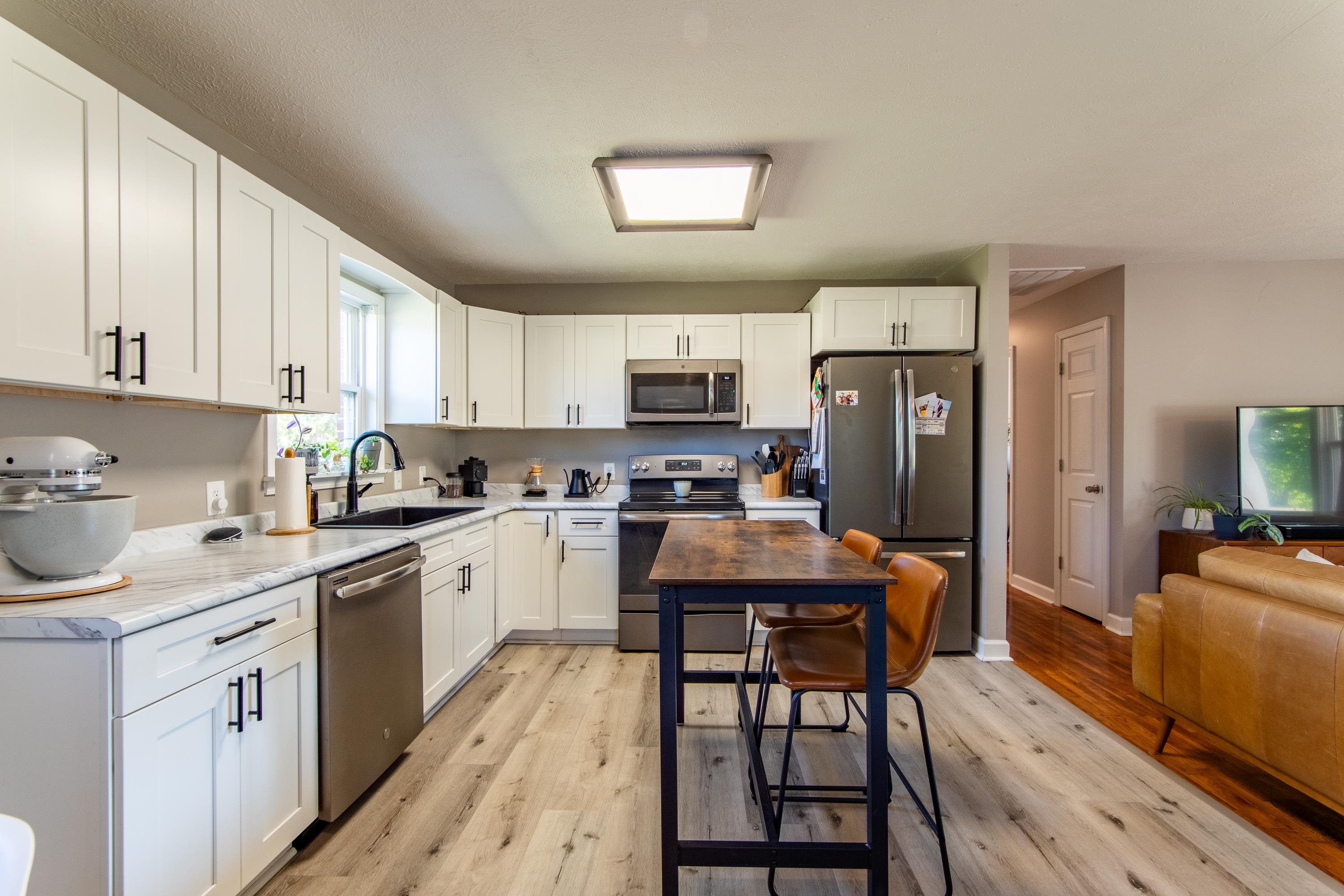 Kitchen with light hardwood / wood-style floors, sink, stainless steel appliances, and white cabinets