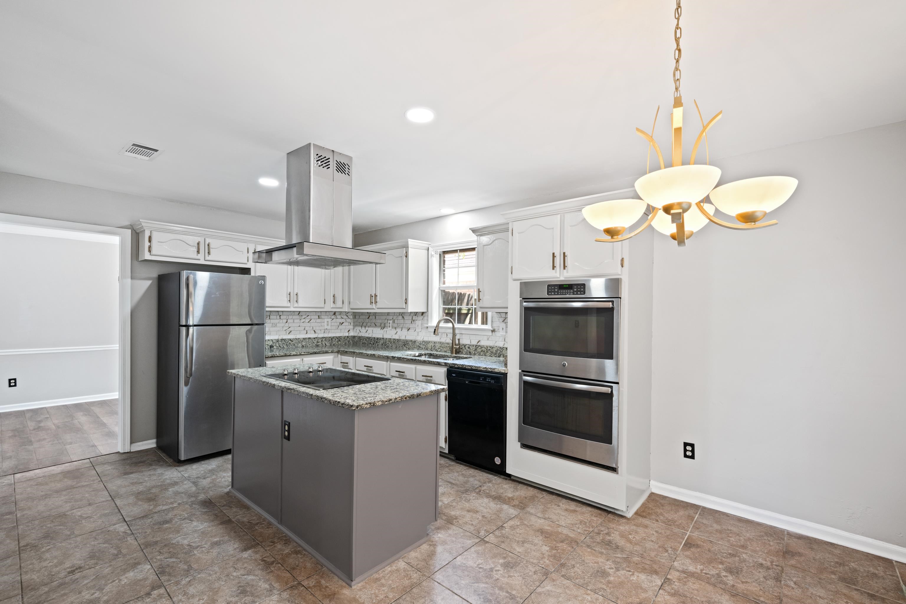 Kitchen with tasteful backsplash, sink, black appliances, island exhaust hood, and a kitchen island