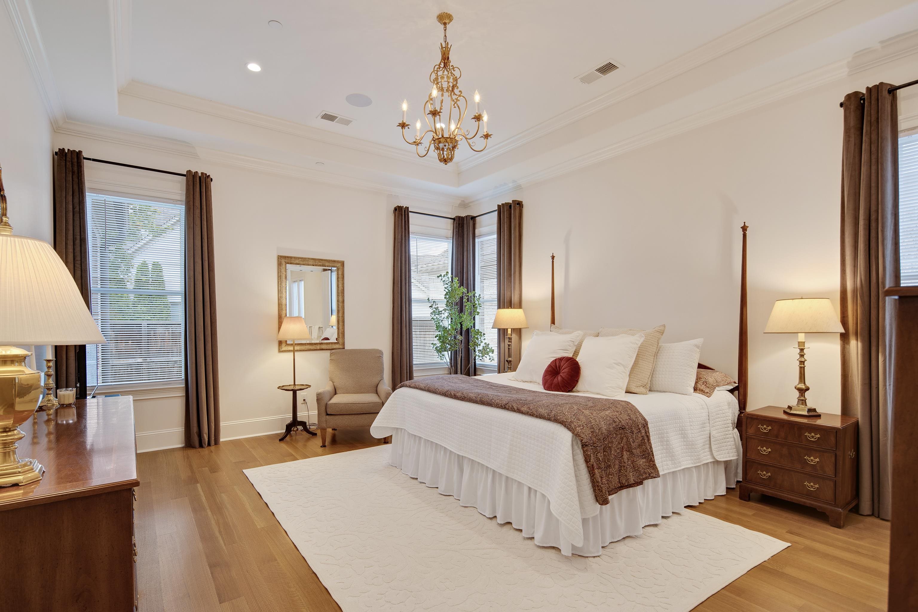 Bedroom featuring a notable chandelier, a raised ceiling, light hardwood / wood-style flooring, and crown molding