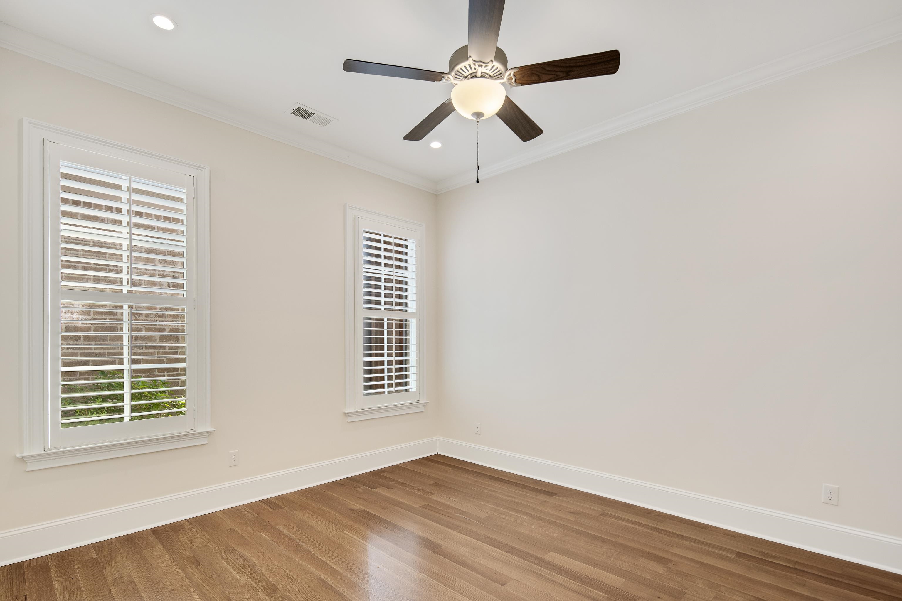 Empty room featuring ceiling fan, wood-type flooring, and ornamental molding