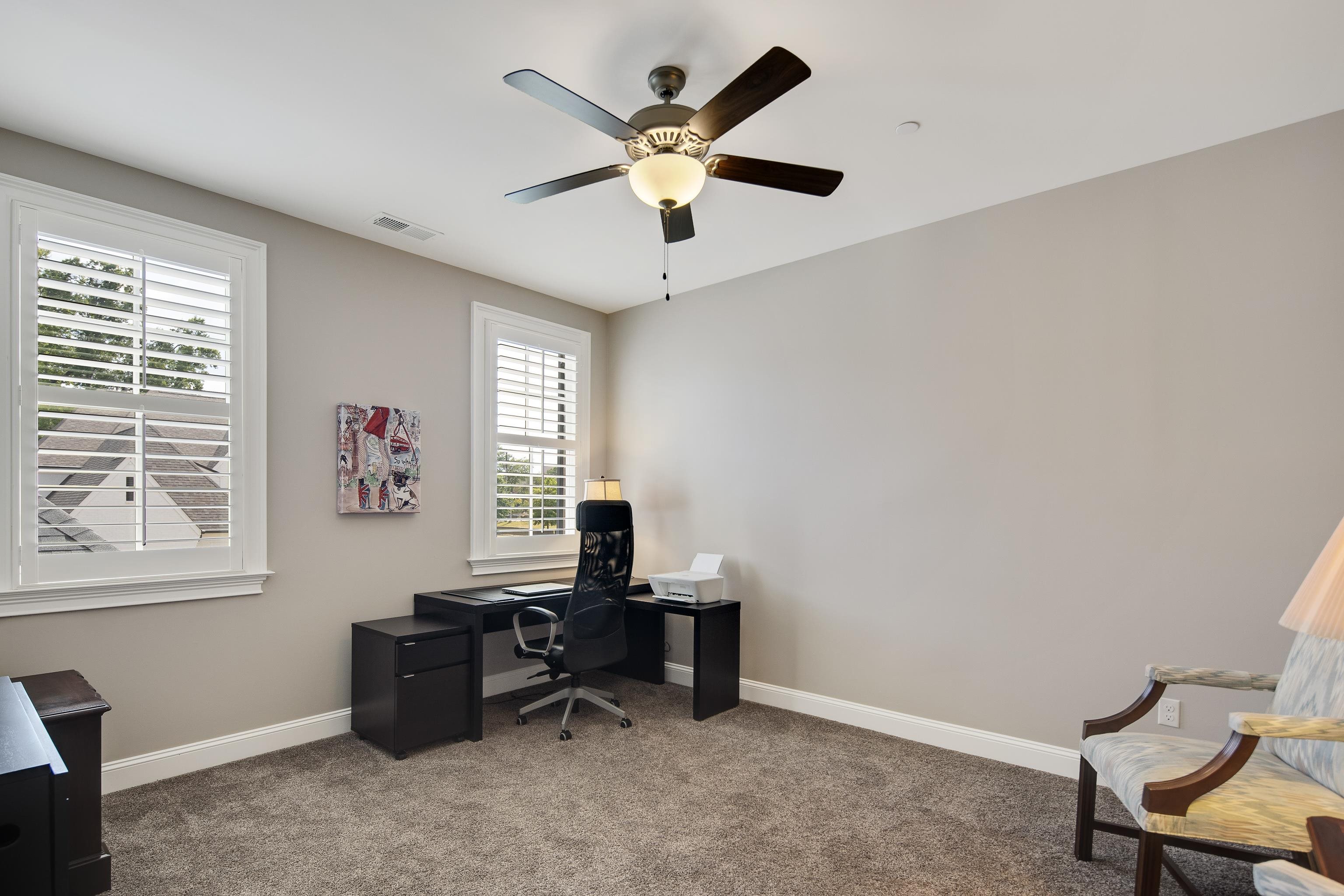 Carpeted office featuring ceiling fan