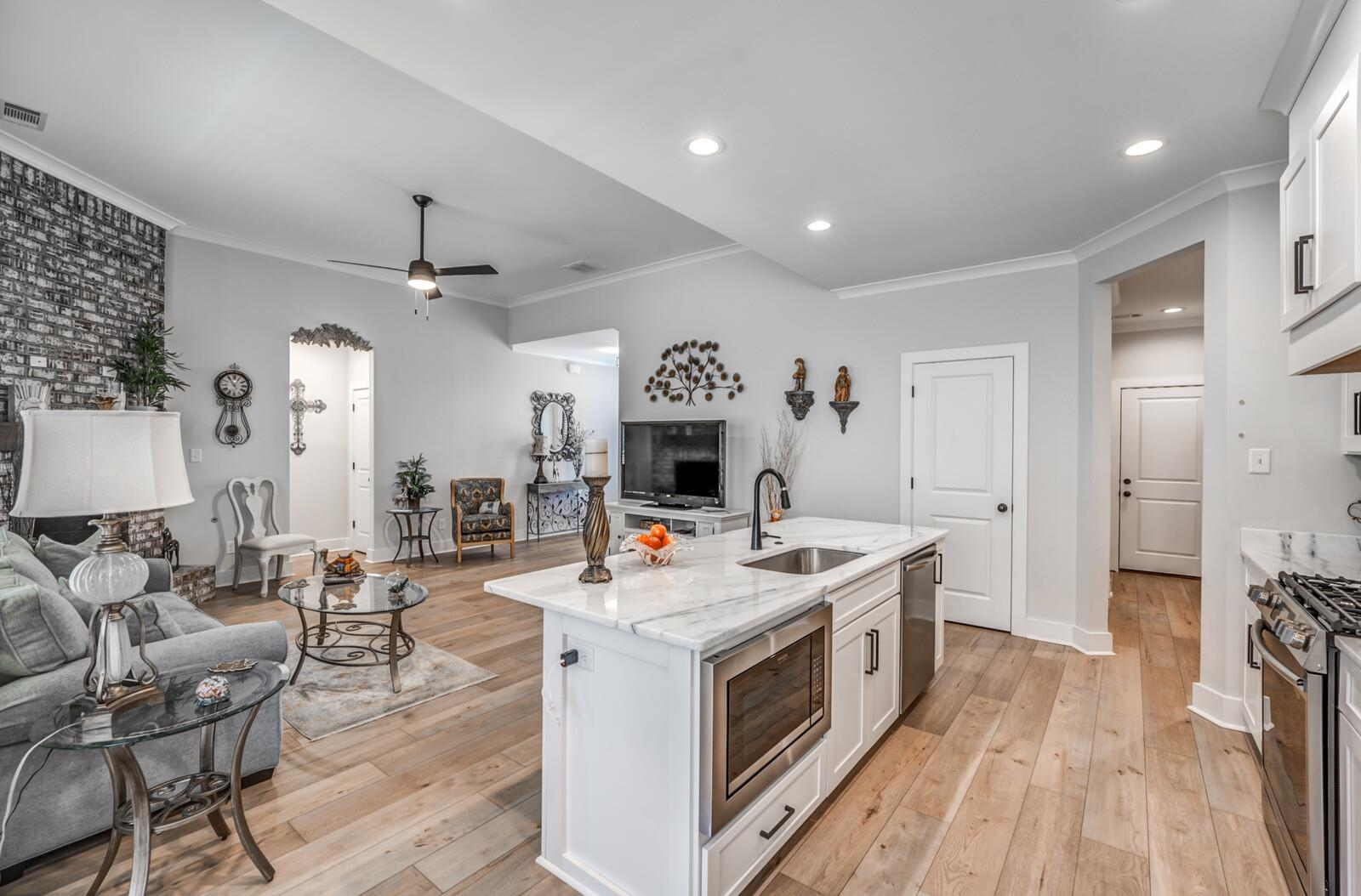 Kitchen featuring sink, light wood-type flooring, ceiling fan, stainless steel appliances, and white cabinets