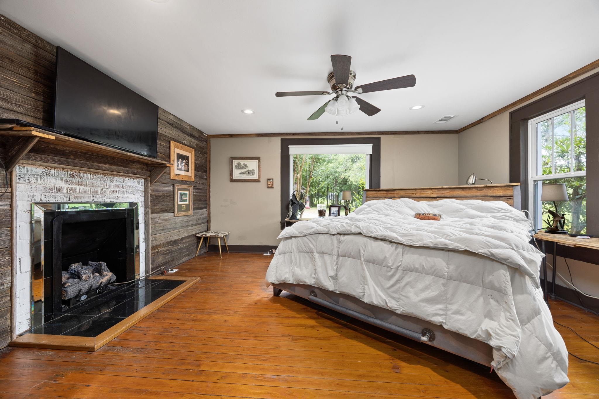 Bedroom with light wood-type flooring, multiple windows, ceiling fan, and ornamental molding