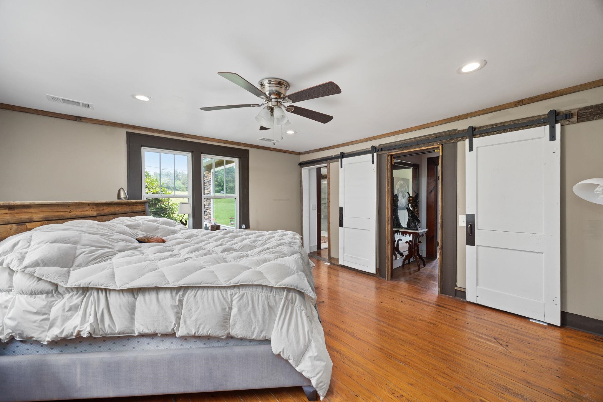 Bedroom featuring crown molding, a barn door, ceiling fan, and hardwood / wood-style floors