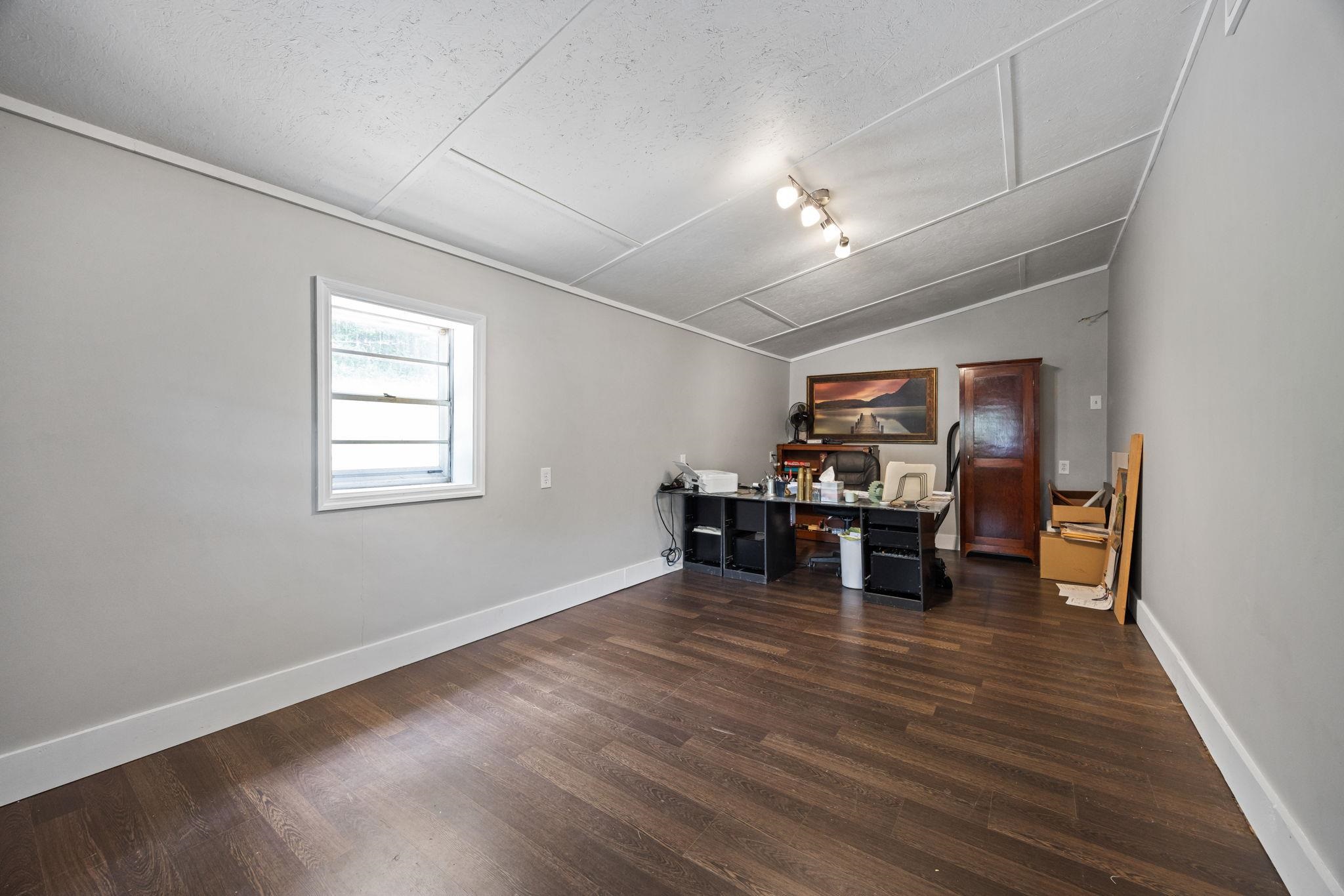 Office area with rail lighting, dark hardwood / wood-style flooring, a textured ceiling, and vaulted ceiling