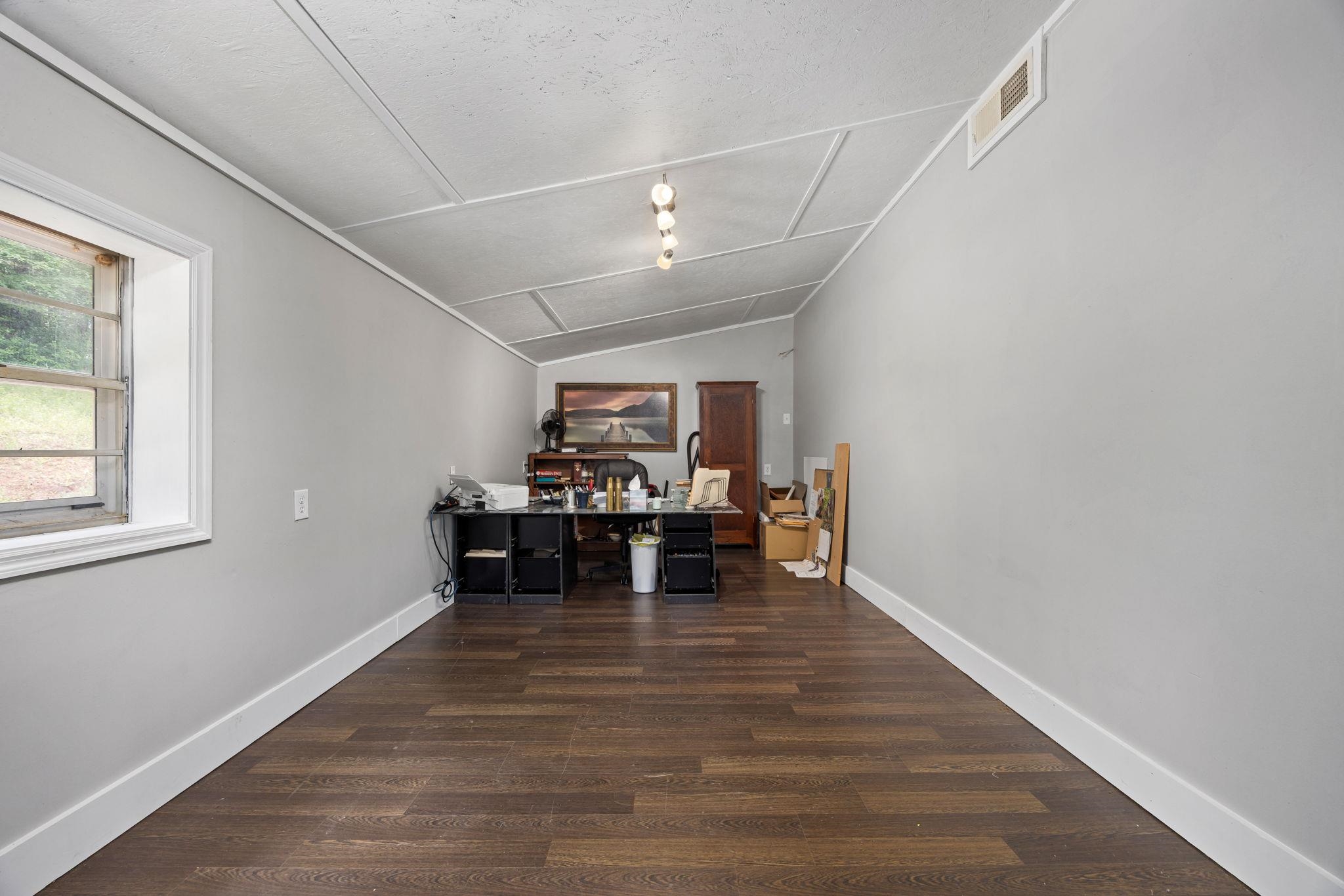 Office with dark hardwood / wood-style flooring, a textured ceiling, and vaulted ceiling