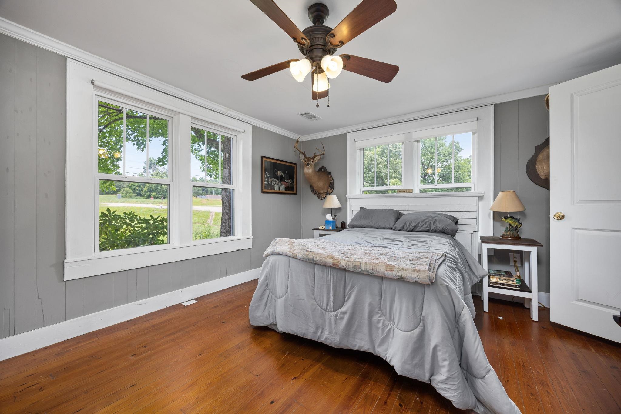 Bedroom with crown molding, multiple windows, ceiling fan, and dark hardwood / wood-style floors