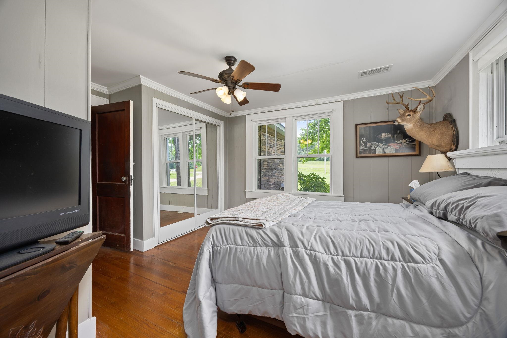 Bedroom with ceiling fan, dark hardwood / wood-style floors, and ornamental molding