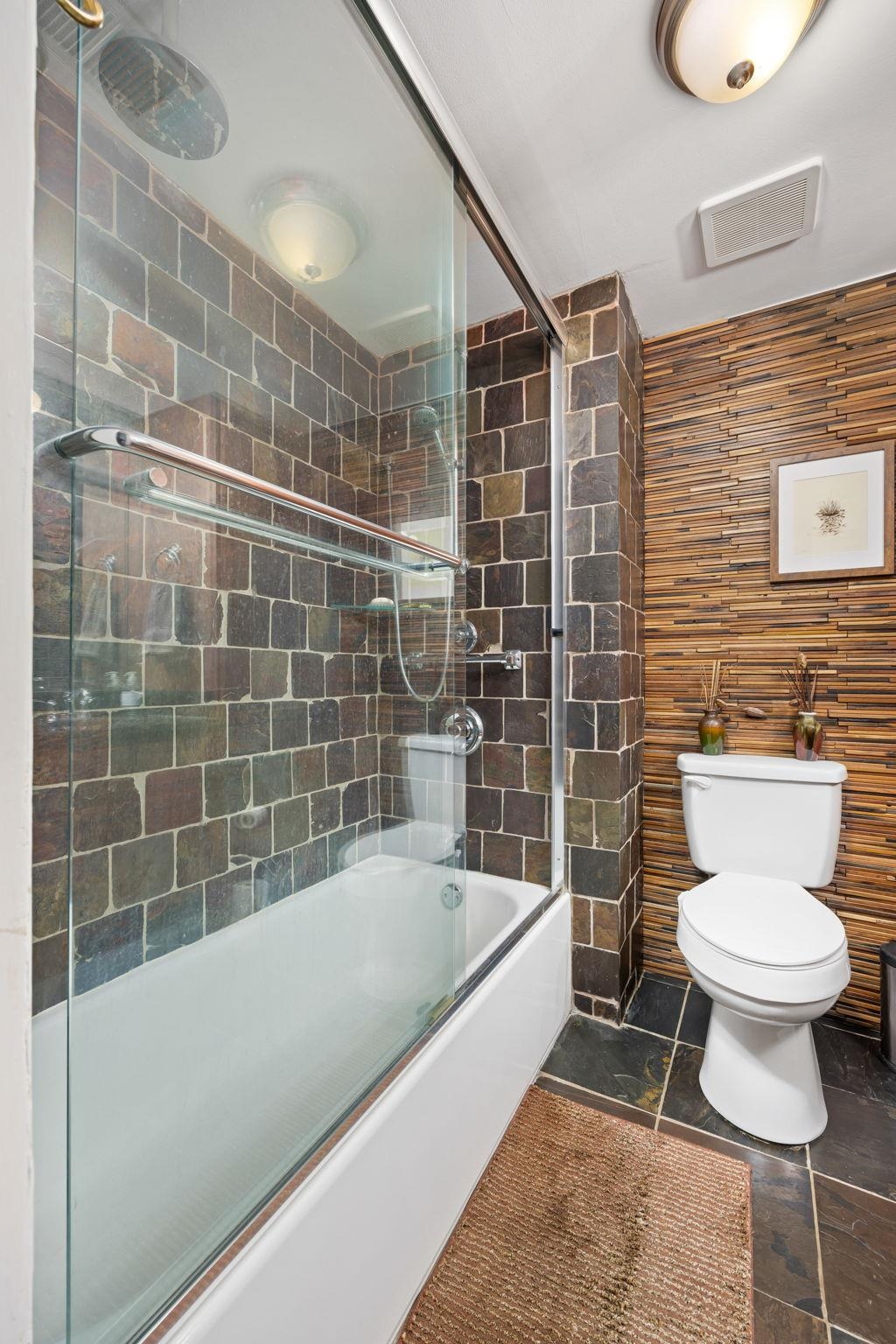 Bathroom with toilet, tile patterned floors, and enclosed tub / shower combo