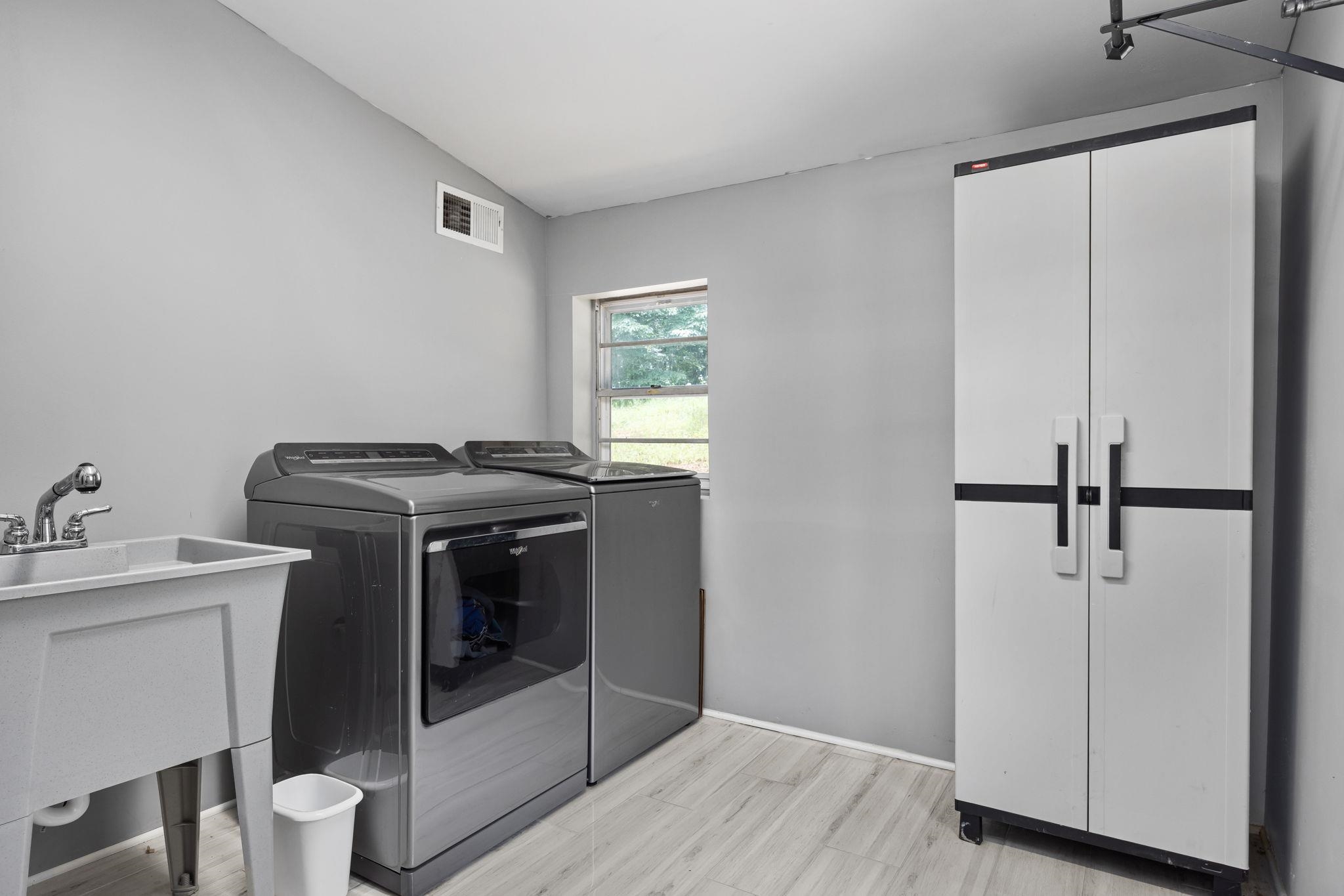 Washroom with washing machine and dryer, sink, and light hardwood / wood-style floors