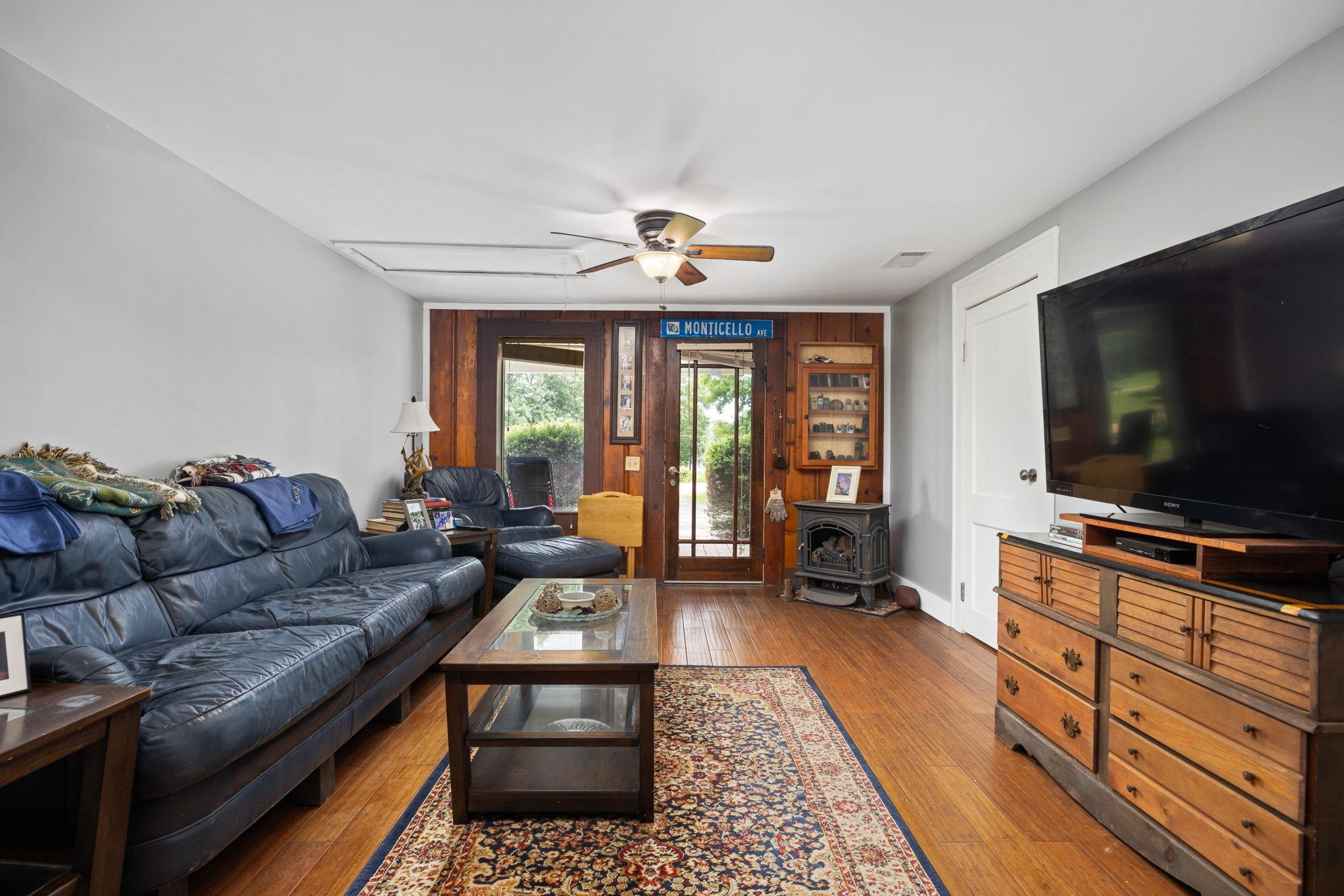 Living room featuring hardwood / wood-style floors, ceiling fan, and a wood stove