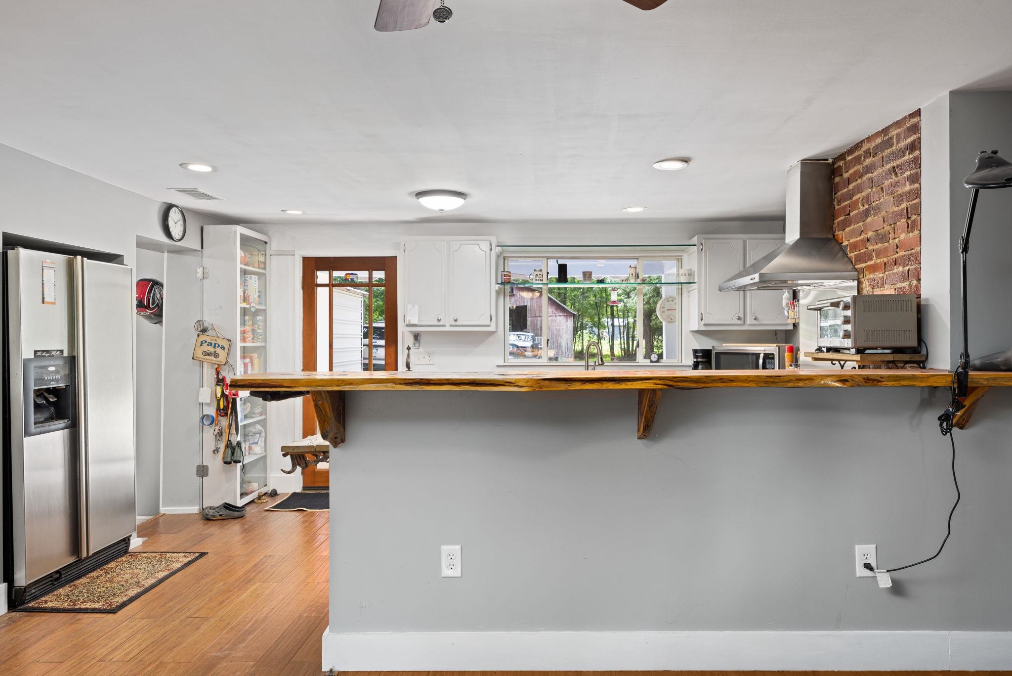 Kitchen featuring appliances with stainless steel finishes, a wealth of natural light, a kitchen breakfast bar, and wall chimney exhaust hood