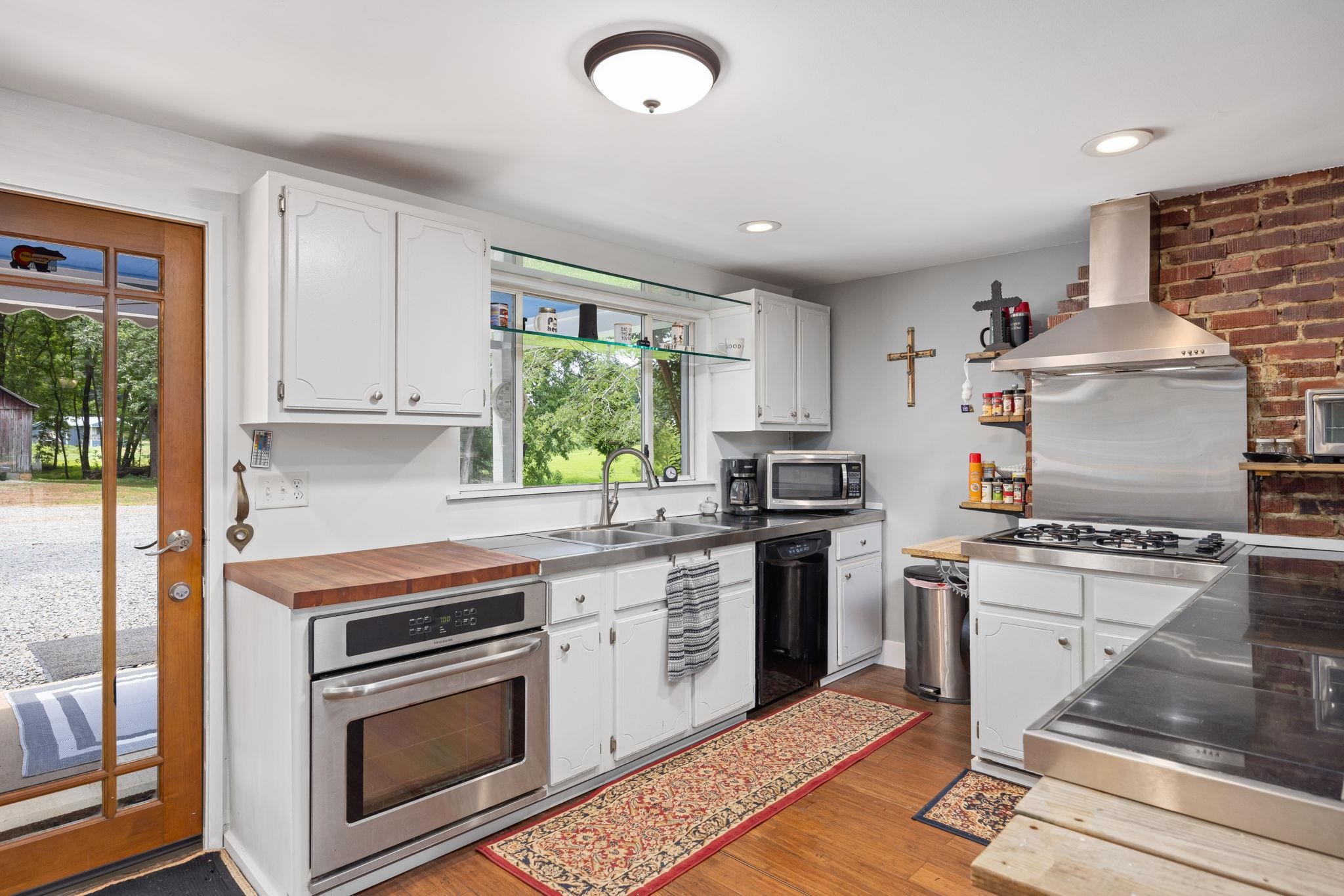 Kitchen with island exhaust hood, light hardwood / wood-style flooring, plenty of natural light, and appliances with stainless steel finishes