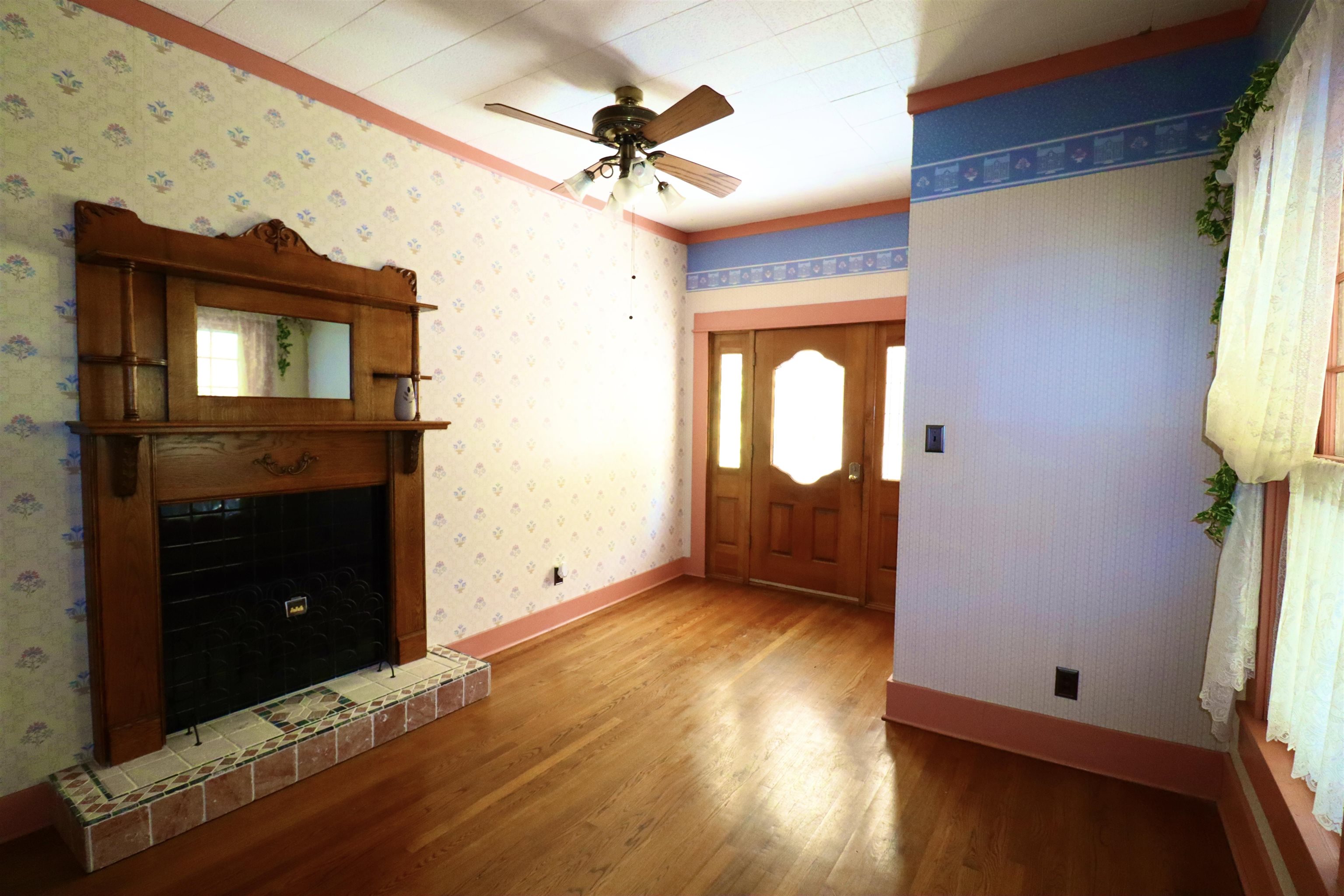 Foyer featuring hardwood / wood-style floors, ceiling fan, and a tiled fireplace