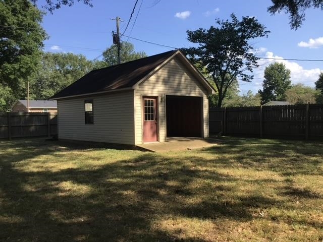 View of outdoor structure featuring a lawn