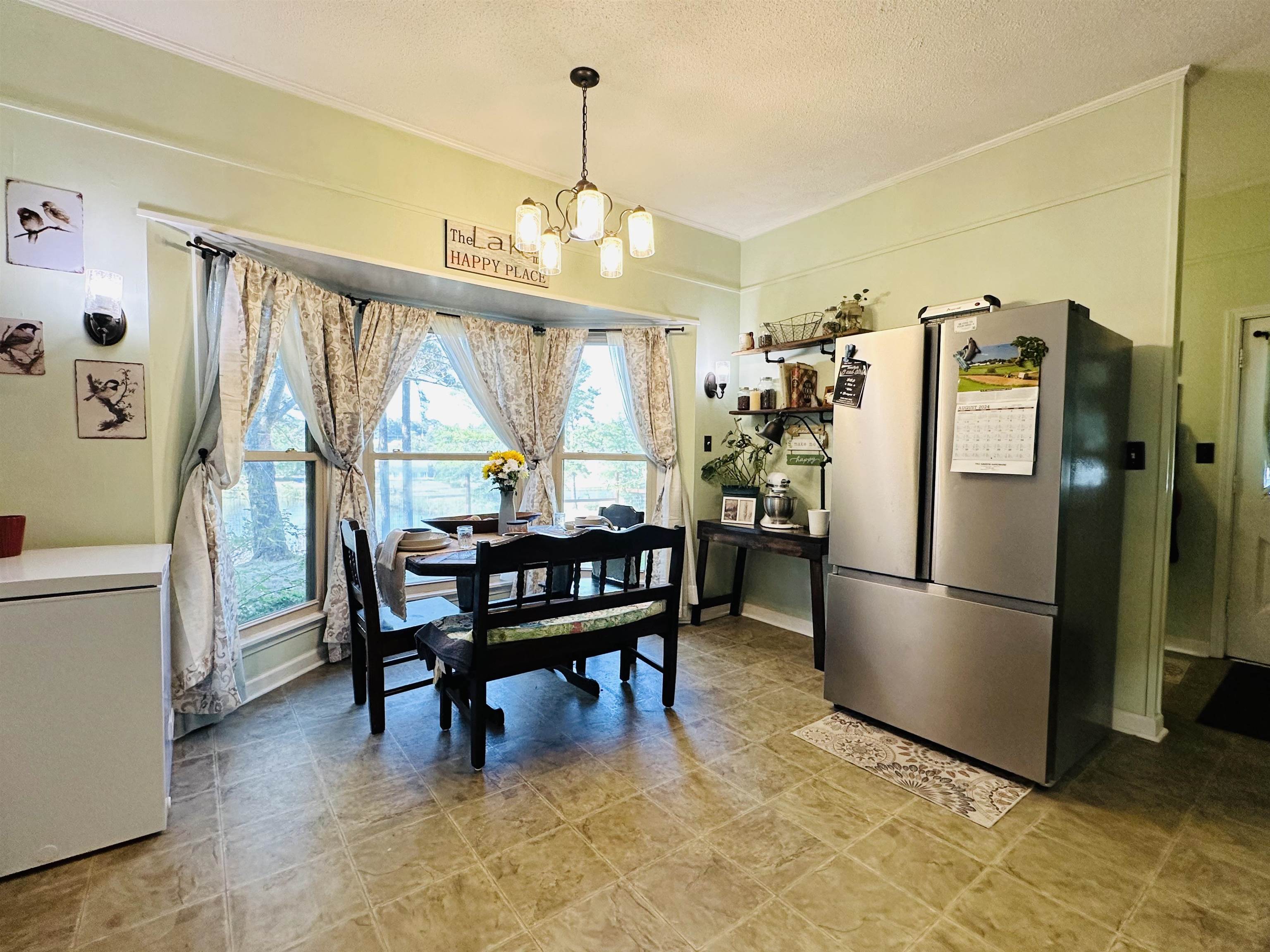 Dining space featuring light tile patterned floors, a notable chandelier, and a textured ceiling