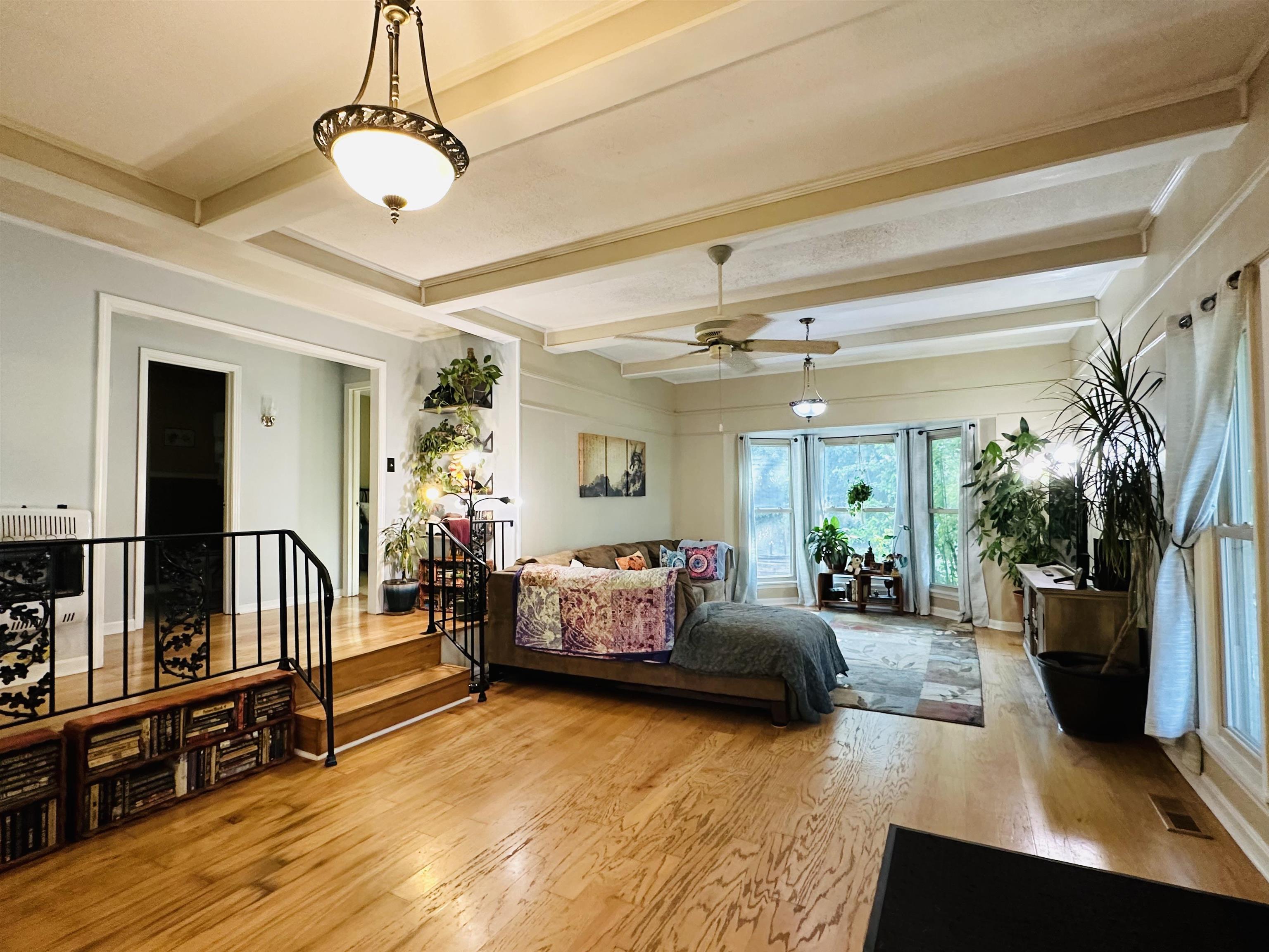 Bedroom with heating unit, beamed ceiling, and light hardwood / wood-style floors