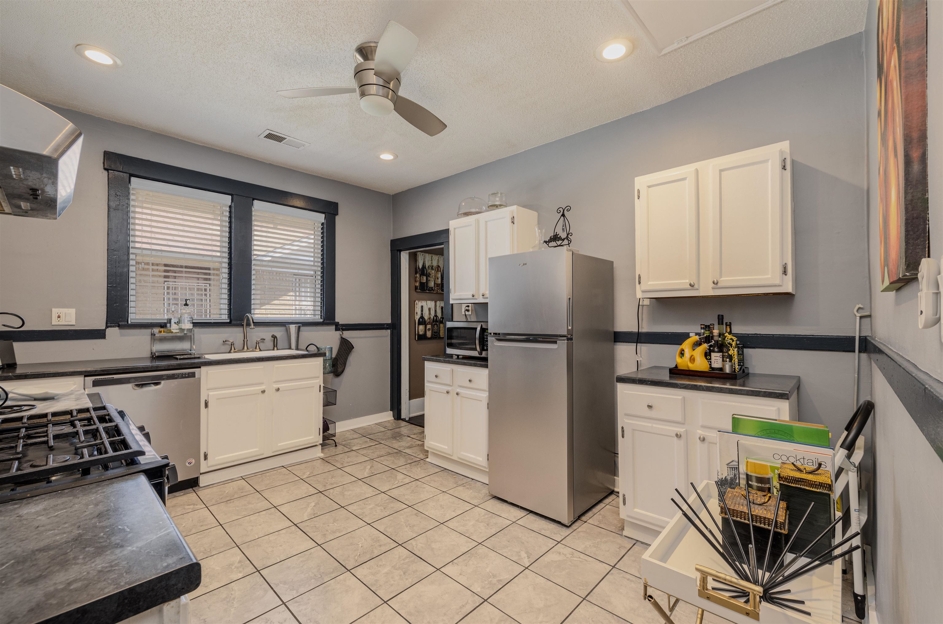 Kitchen with white cabinetry, stainless steel appliances, sink, ceiling fan, and light tile patterned flooring