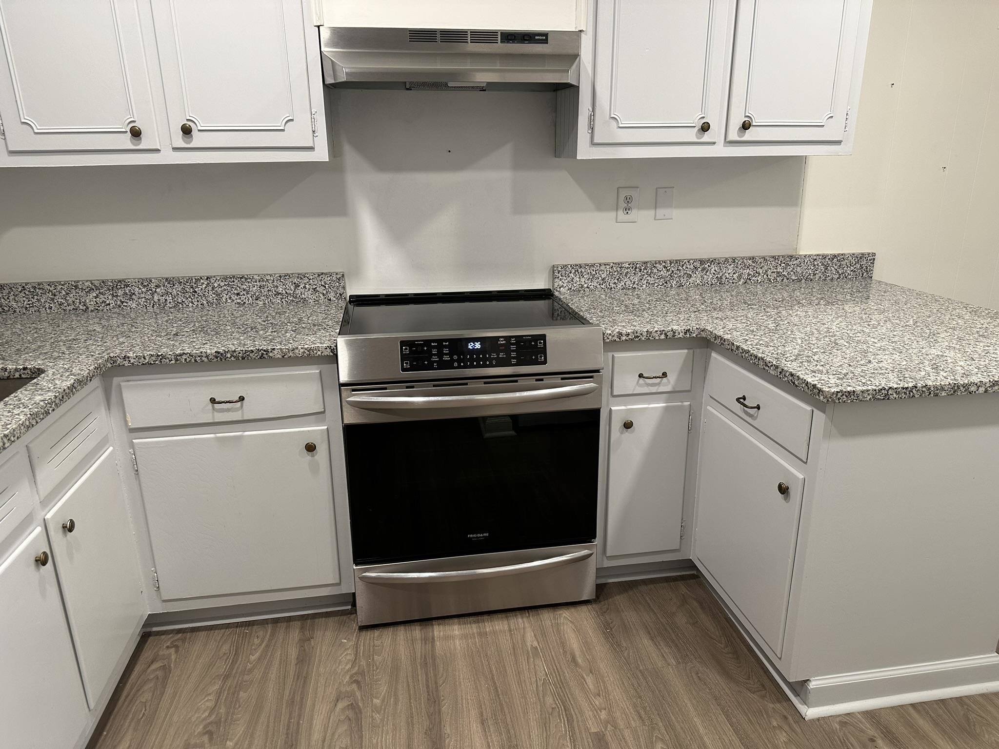 Kitchen featuring hardwood / wood-style flooring, stainless steel electric range, and white cabinets