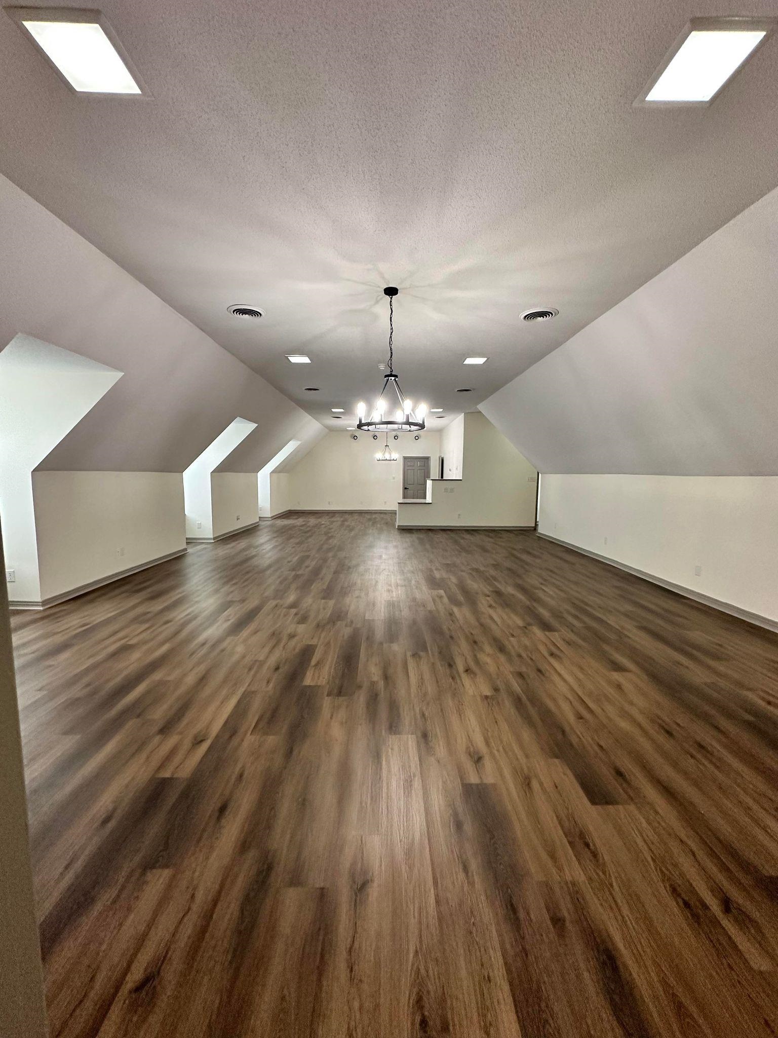 Bonus room featuring vaulted ceiling, dark hardwood / wood-style flooring, a chandelier, and a textured ceiling