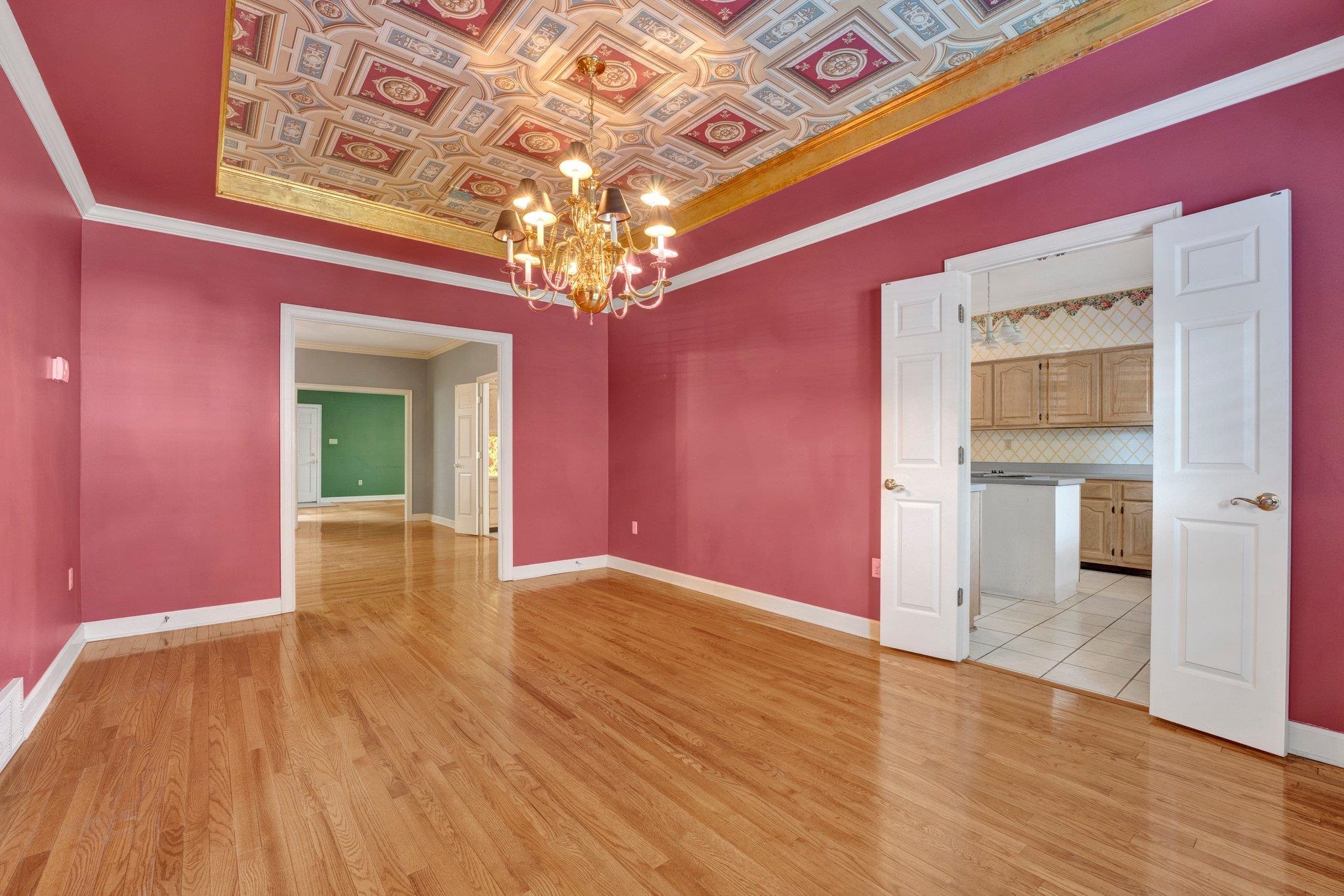 Unfurnished room with light wood-type flooring, a raised ceiling, and a notable chandelier