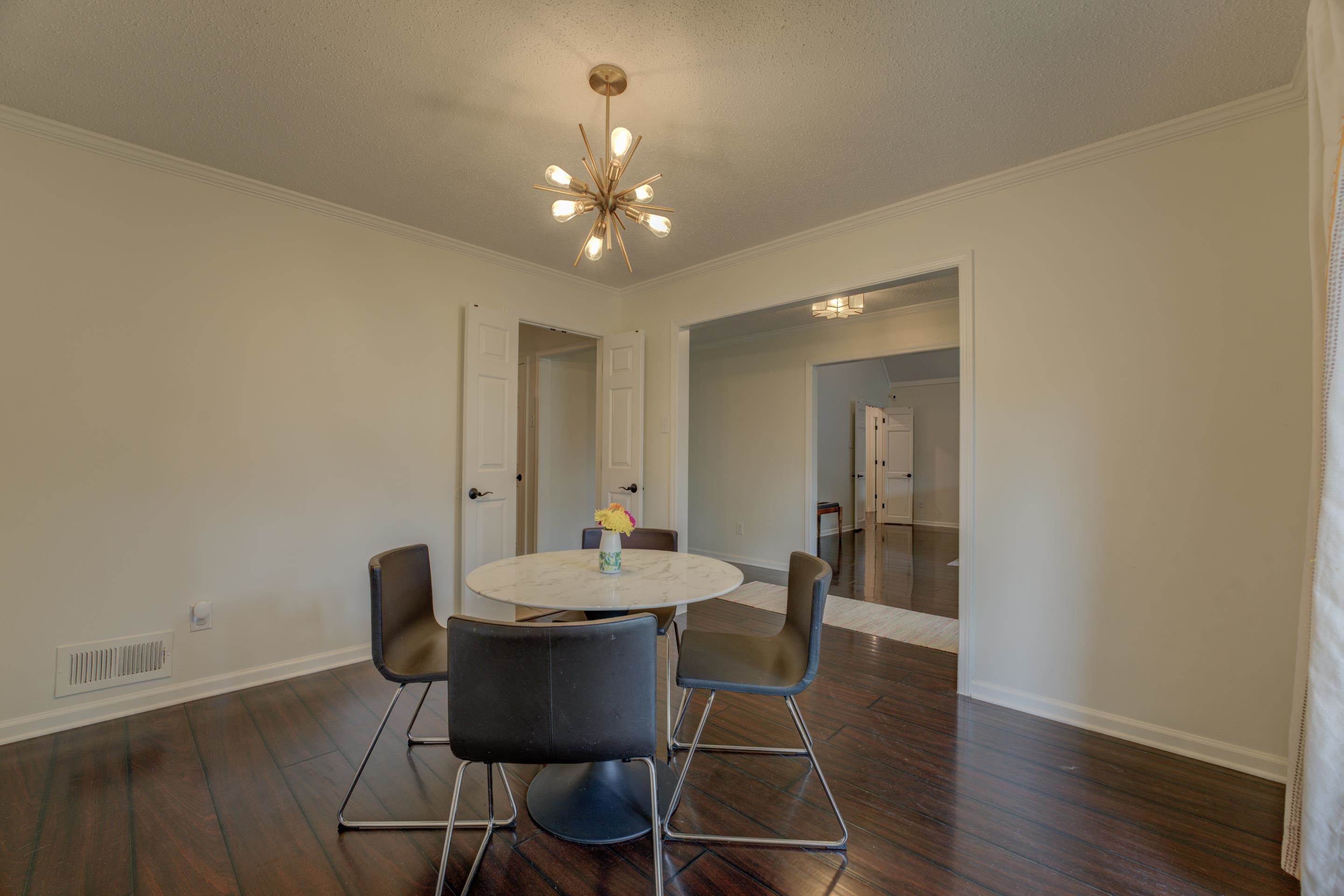 Dining space with a chandelier, dark hardwood / wood-style flooring, and ornamental molding