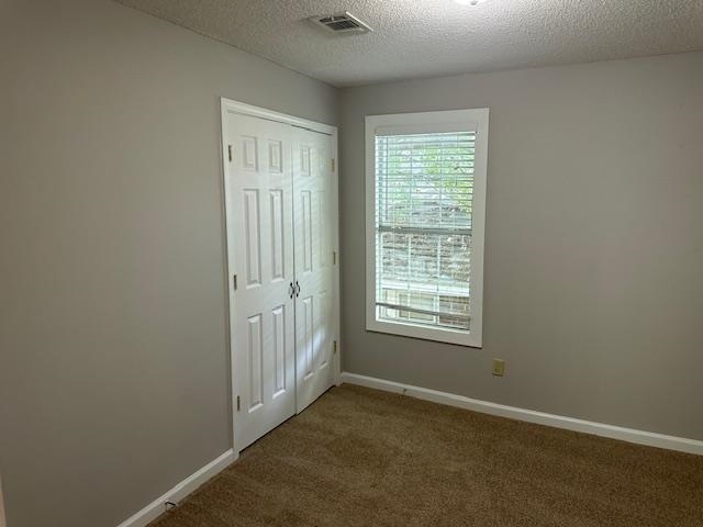 Unfurnished bedroom with a closet, carpet, and a textured ceiling