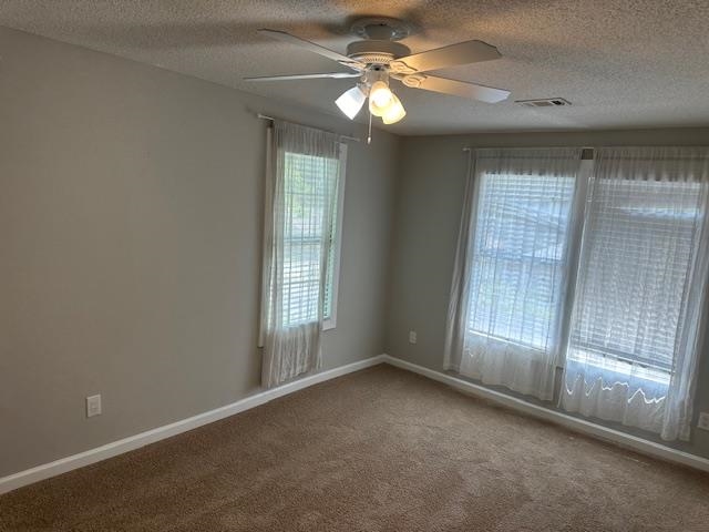 Carpeted empty room featuring ceiling fan and a textured ceiling