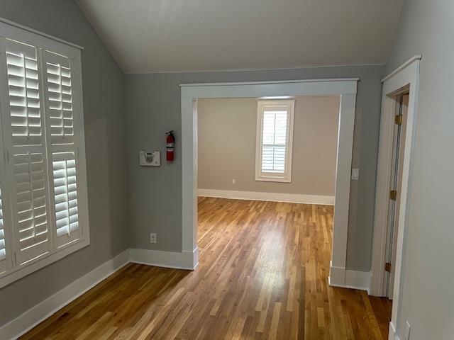 Corridor featuring vaulted ceiling and hardwood / wood-style floors